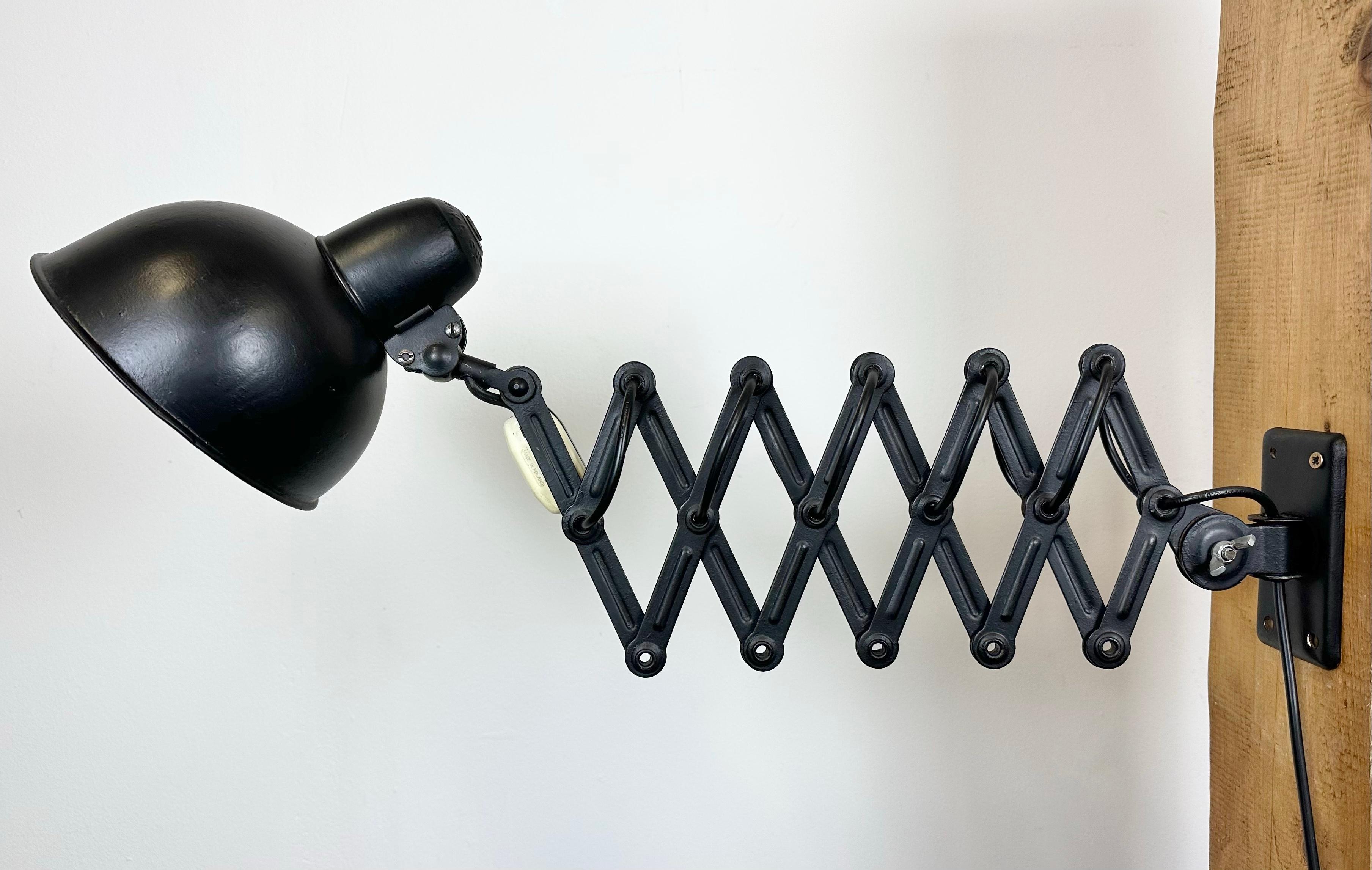 This industrial Bauhaus scissor wall light designed by Christian Dell and produced by Kaiser Idell in Germany during the 1930s is made of black -painted metal. The iron scissor arm is extendable and can be turned sideways. The original socket