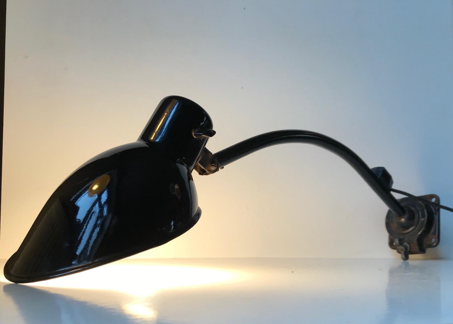This wall or desk lamp was designed by Bauhaus Icon Marianne Brandt. It was manufactured by German Kandem in the 1930s. The adjustable arm is made from black lacquered steel and the shade is enameled Steel. It has a large rotating ball joint at the