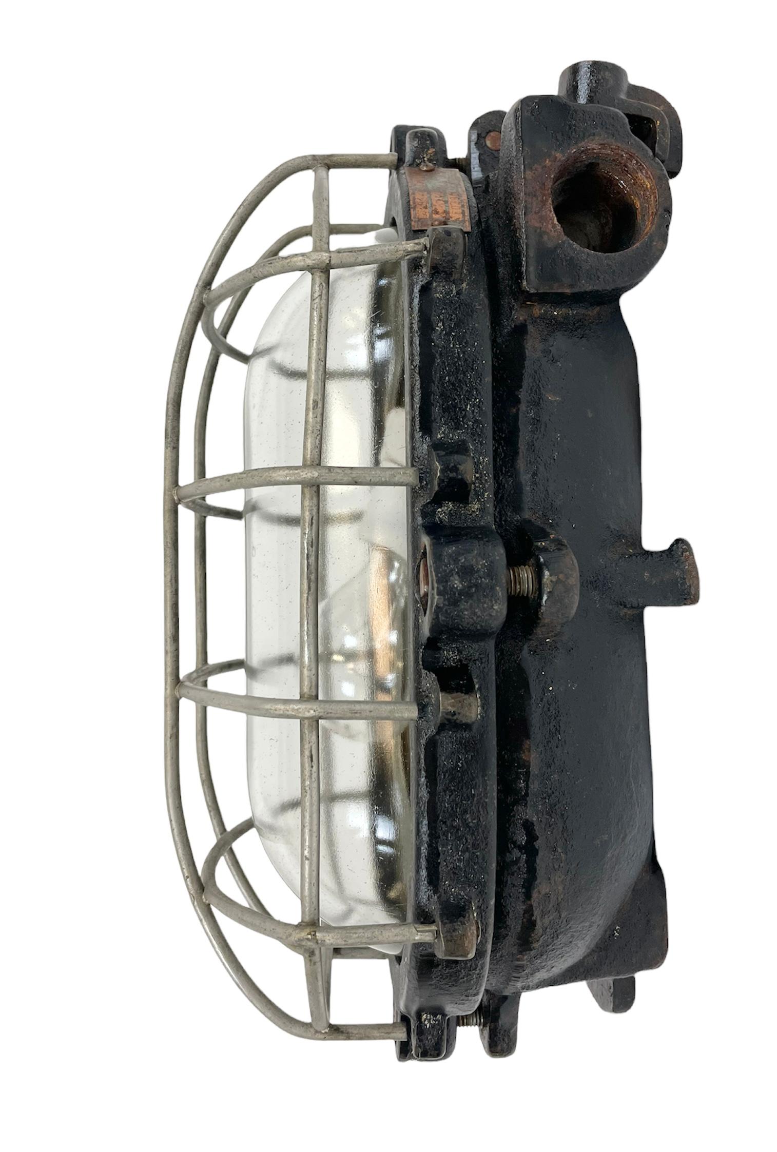 Industrial wall light made by Elektrosvit in former Czechoslovakia during the 1960s. It features a cast iron body, a clear glass cover and a steel grid.The porcelain socket requires E 27 light bulbs. New wire. The weight of the light is 7 kg.