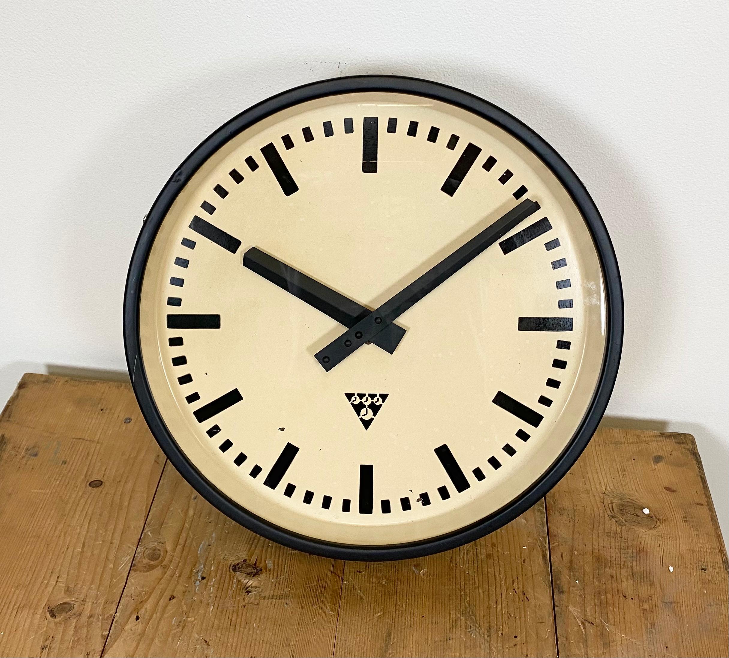 These Pragotron wall clock was made in former Czechoslovakia during the 1960s. Features a black iron frame, metal dial, aluminium hands and clear glass cover. The piece has been converted into a battery-powered clockwork and requires only one