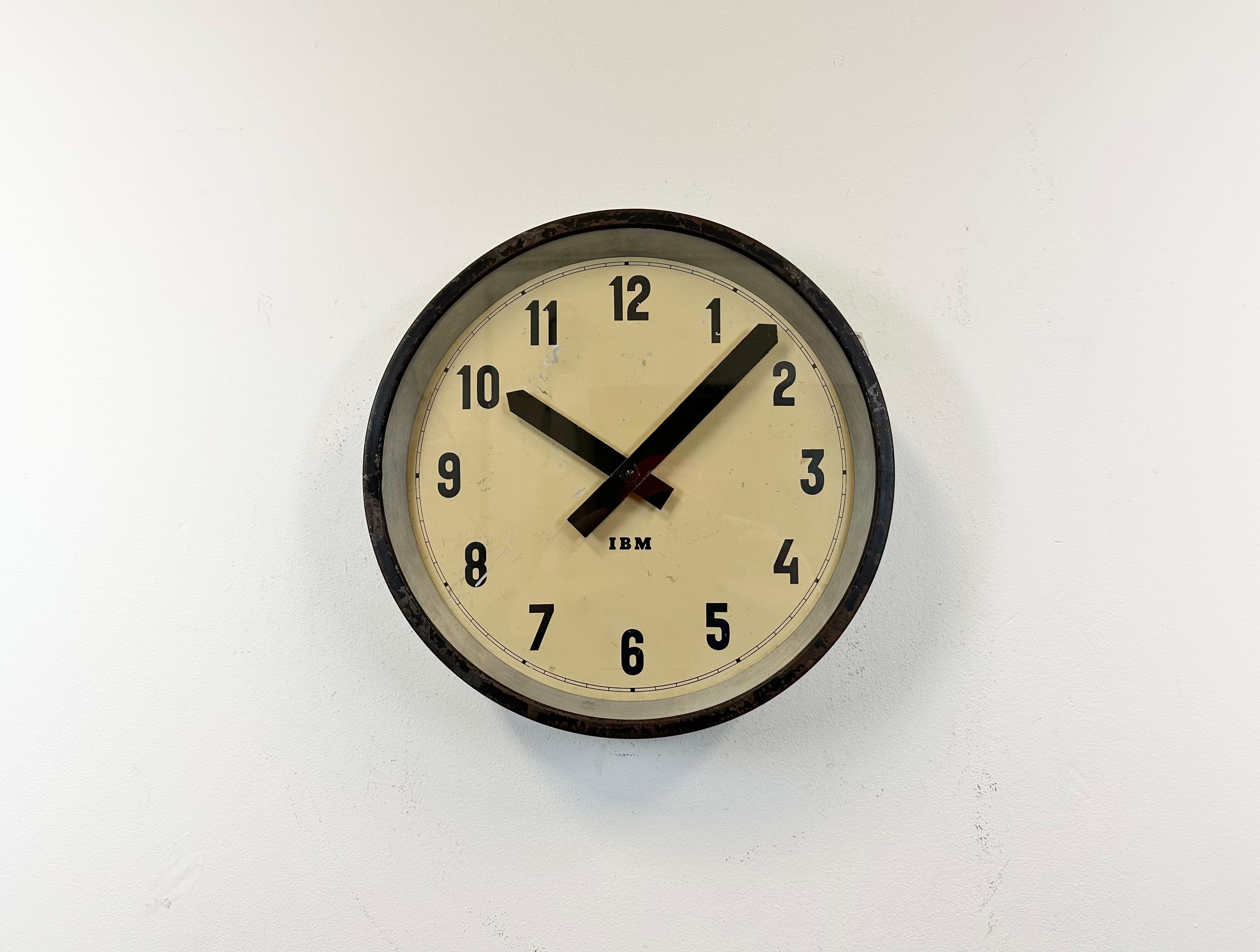 This wall clock was produced by IBM in USA during the 1950s. It features a black metal frame, iron dial, aluminium hands and a clear glass cover. The piece has been converted into a battery-powered clockwork and requires only one AA-battery. The
