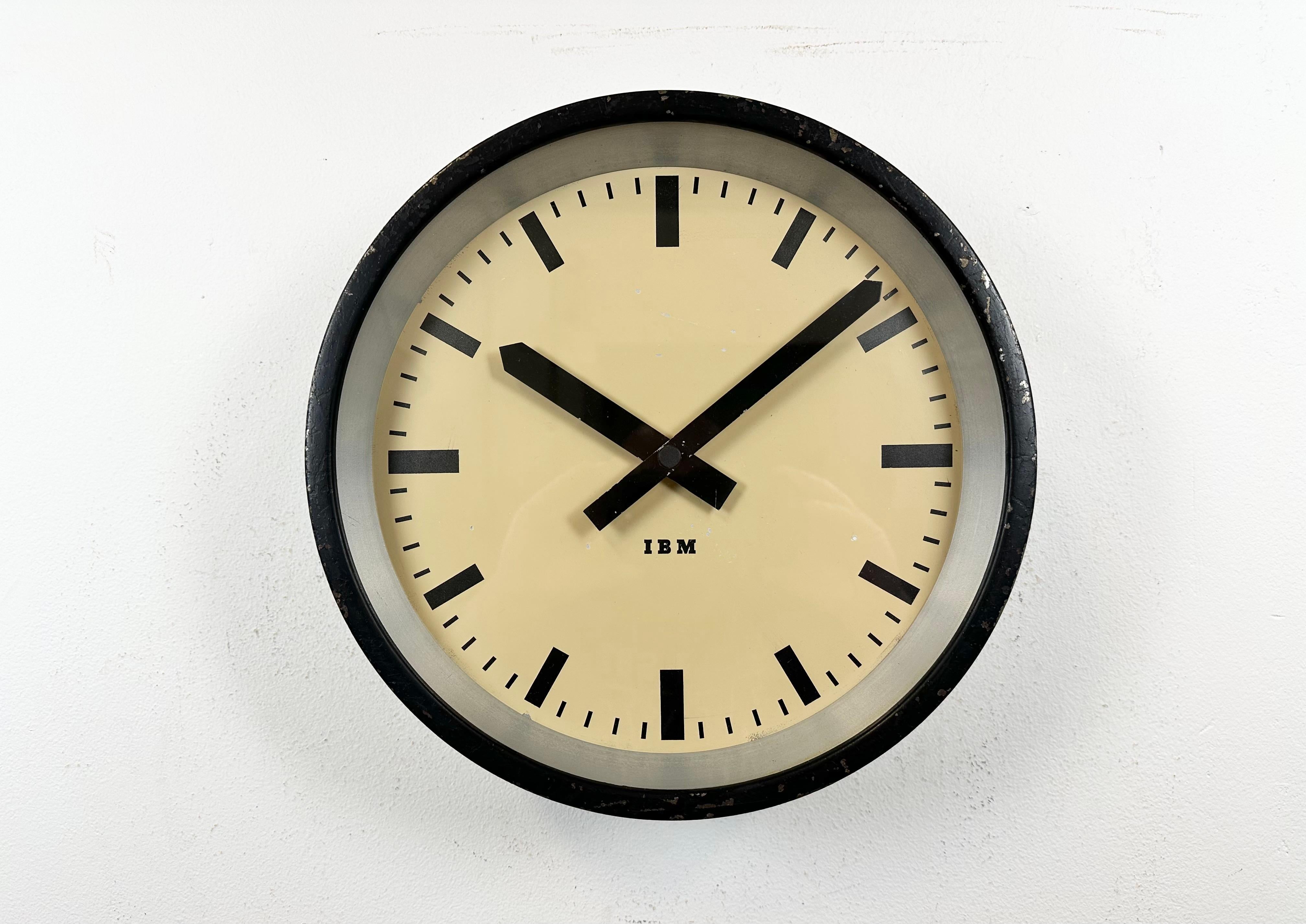 
This wall clock was produced by IBM in the USA during the 1950s. It features a black metal frame, iron dial, aluminium hands and a clear glass cover. The piece has been converted into a battery-powered clockwork and requires only one AA-battery.