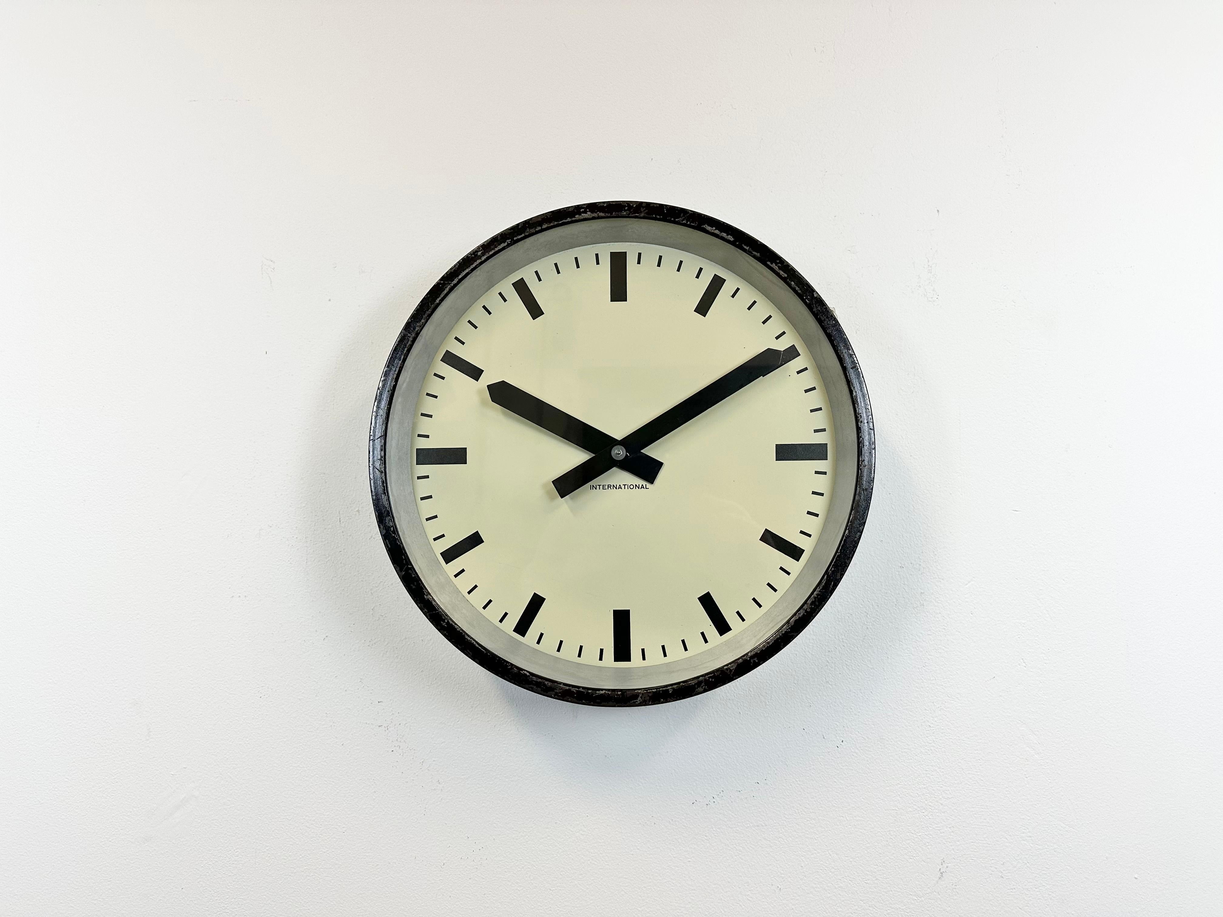 This wall clock was produced by International in Germany during the 1950s. It features a black metal frame, iron dial, aluminium hands and a clear glass cover. The piece has been converted into a battery-powered clockwork and requires only one