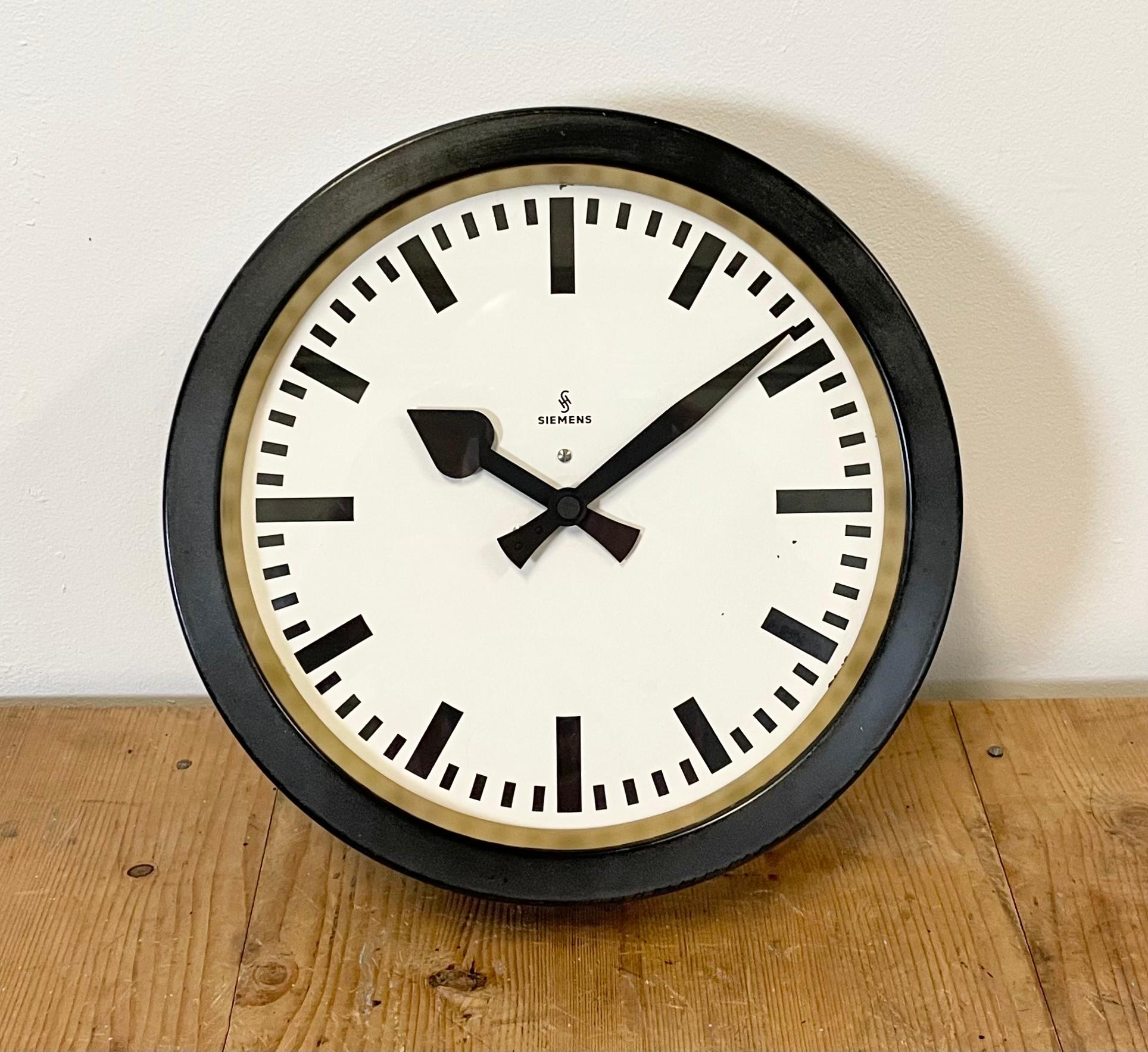 This wall clock was produced by Siemens in Germany during the 1950s. It features a black metal frame, a metal dial and a clear glass cover. The piece has been converted into a battery-powered clockwork and requires only one AA-battery. The weight of