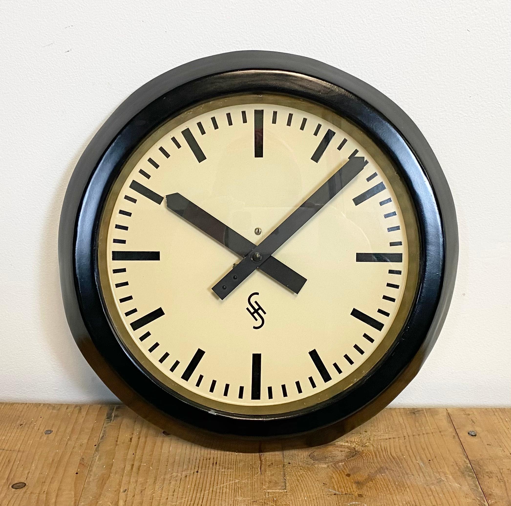 This wall clock was produced by Siemens and Halske in Germany during the 1950s. It features a black metal frame, aluminum dial, and a clear glass cover. The piece has been converted into a battery-powered clockwork and requires only one