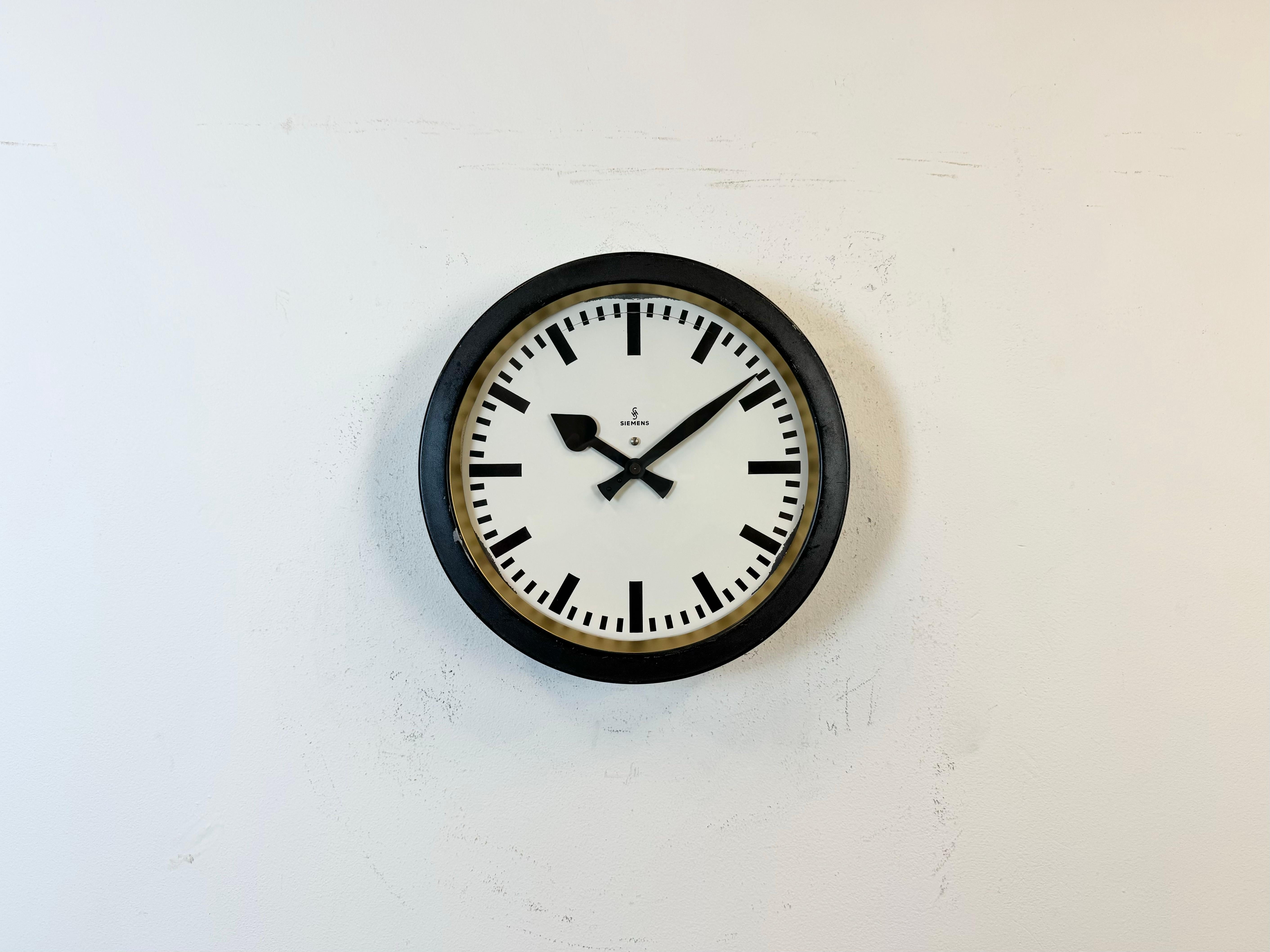 This wall clock was produced by Siemens in Germany during the 1950s. It features a black metal frame, a metal dial and a clear glass cover. The piece has been converted into a battery-powered clockwork and requires only one AA-battery. The weight of