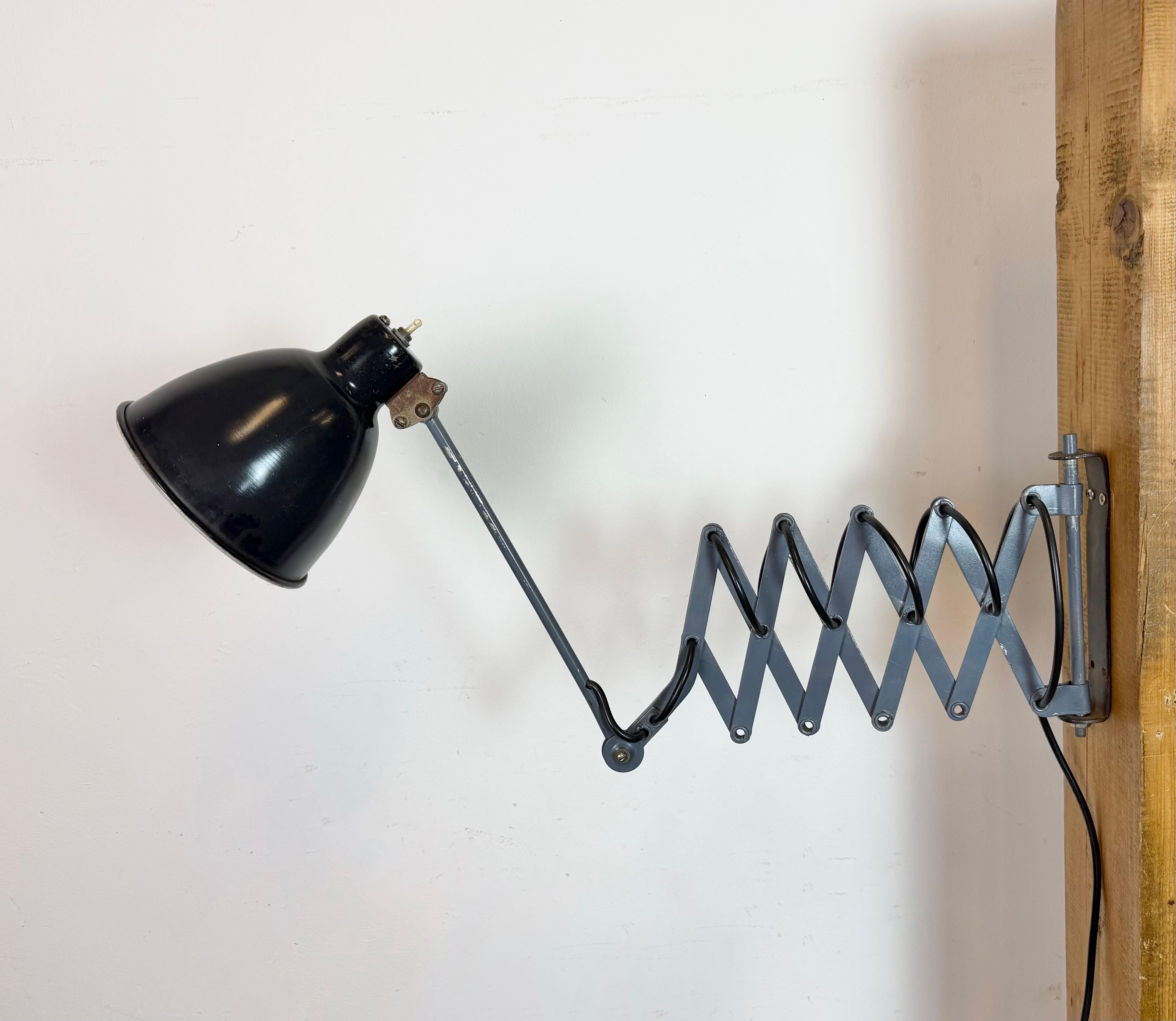 This vintage industrial grey scissor wall light was made in Ukraine in former Soviet Union during the 1960s. It features a black metal shade with original switch. The grey scissor arm is extendable and can be turned sideways. The socket requires E27