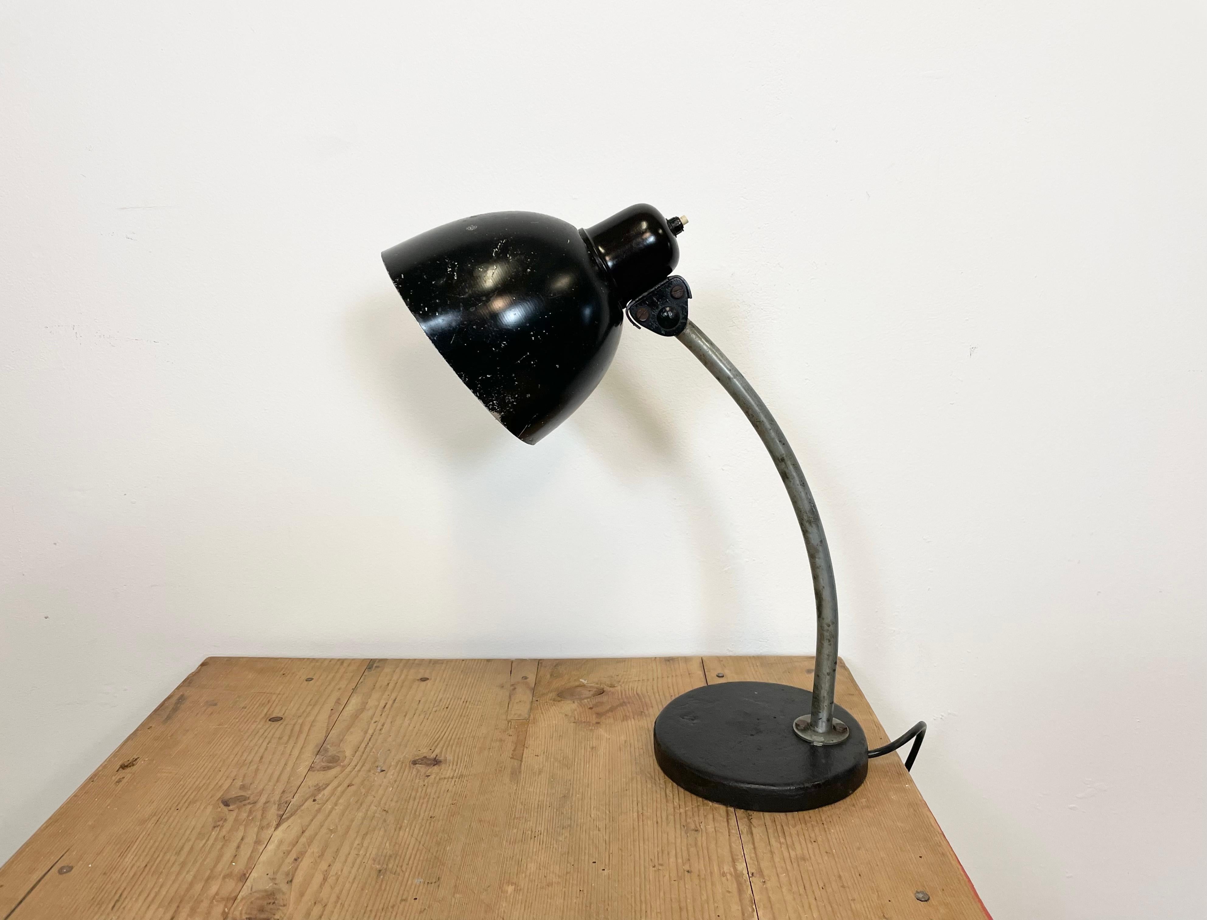 This black industrial workshop desk lamp was made in former Czechoslovakia during the 1950s. The lamp has an adjustable black aluminium shade with bakelite top, an iron base and arm.The socket requires E 27/ E 26 lightbulbs. New wire. Fully
