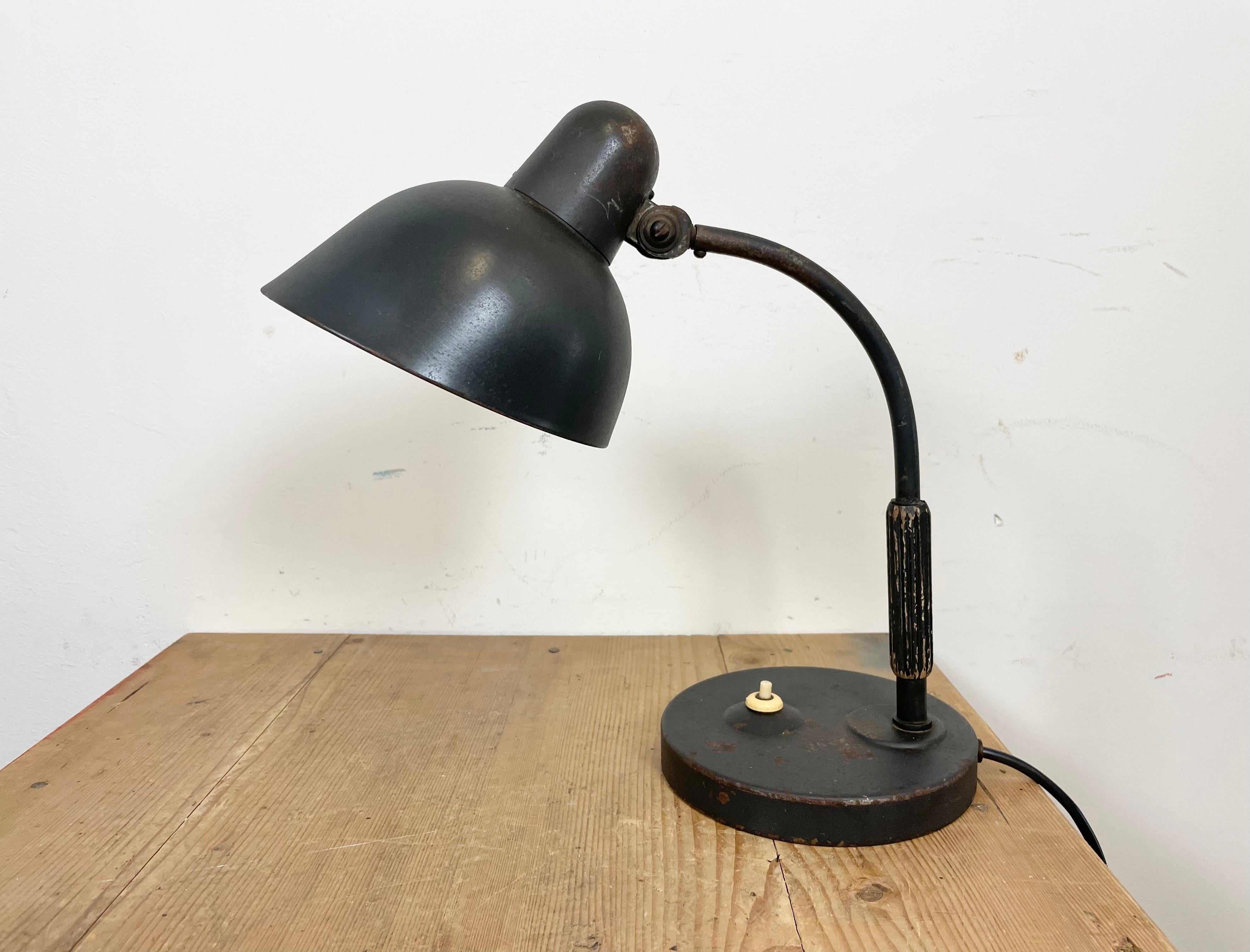 Black Bauhaus table lamp made in Germany by Siemens during the 1930s. The lamp has an adjustable metal shade, an iron base and an iron arm with wooden handle. The original socket requires E 27/ E26 lightbulbs. The weight of the lamp is 1,4 kg.