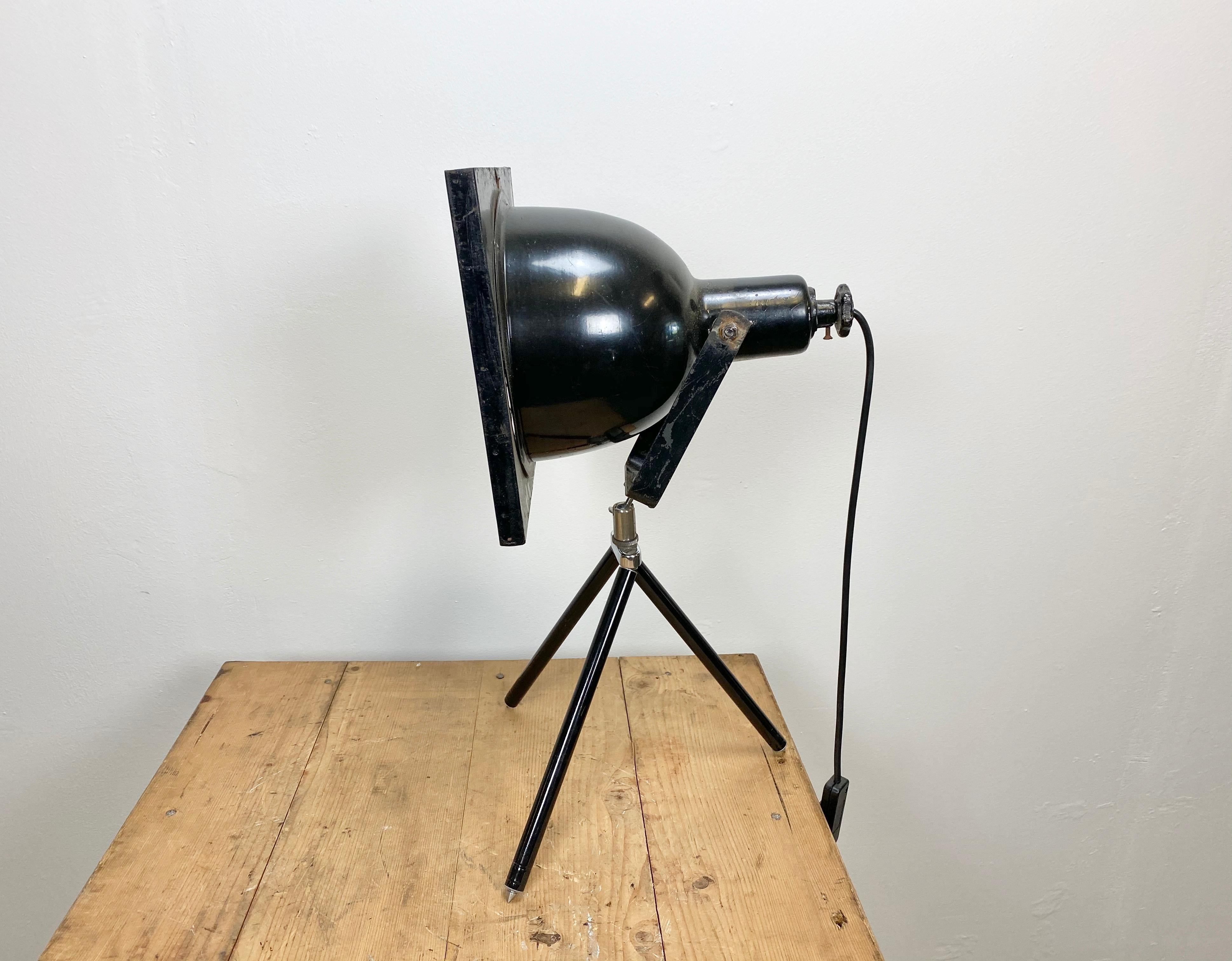 Industrial table lamp from 1960s. Black theatre spotlight on a small iron tripod. The lamp has a porcelain socket for E 27 light bulbs and new wire. Fully functional.