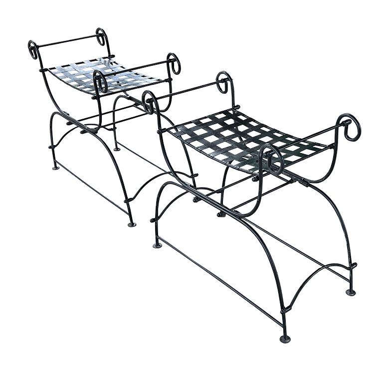 A pair of Italian black metal carule style benches in the manner of Salterini. Each bench features curled arms and lattice style seats. This set would be fabulous in a living room next to a fire, perhaps with Scalamandre le Tigre cushions. Or, they