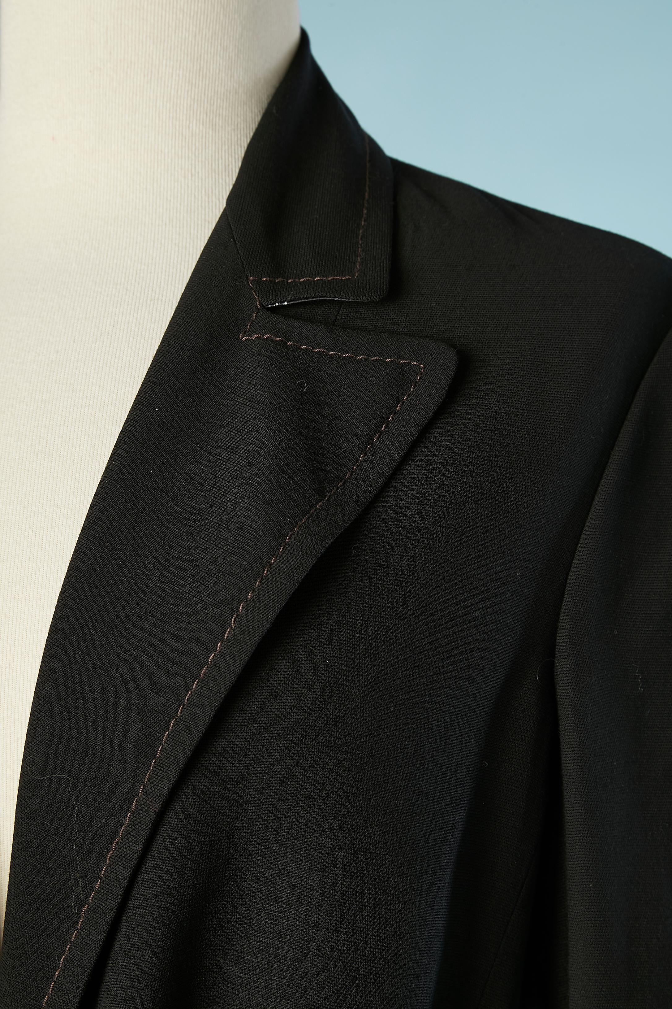 Ensemble veste noire et jupe enveloppante en soie imprimée. Ceinture en tissu imprimé (identique à la jupe) à la taille de la veste. Un bouton marqué pour le fermer. Surpiqûres sur le col et les poches. L'étiquette de composition du tissu a été