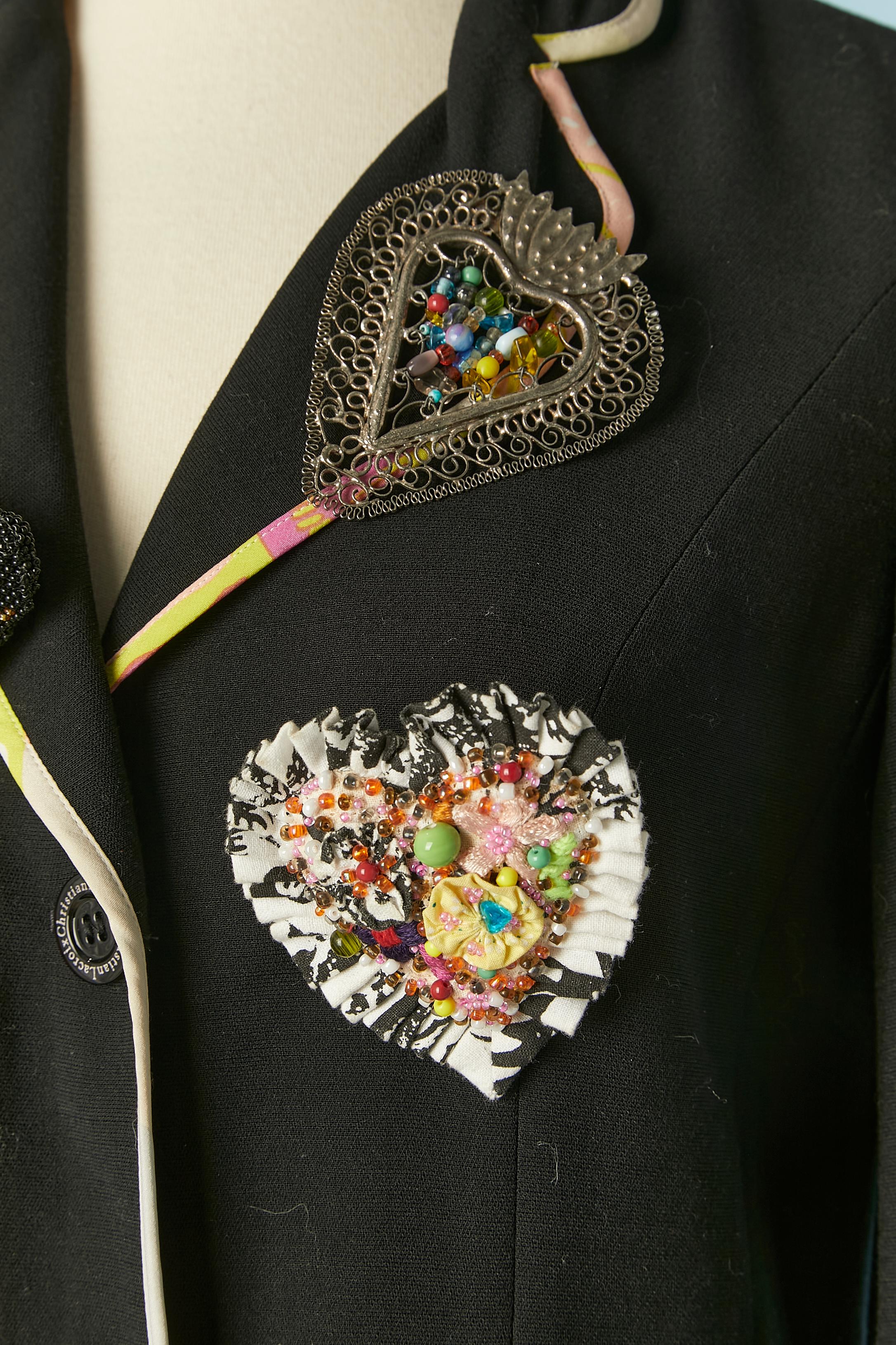 Schwarze Jacke mit Paspelierung und Broschen-Verzierung. Zusammensetzung des Hauptgewebes: 52% Wolle, 48% Viskose. Futter: 65% Acetat, 35% Viskose. Knopf mit Markenzeichen. Taschen auf beiden Seiten. 
SIZE 38 (Fr) M 