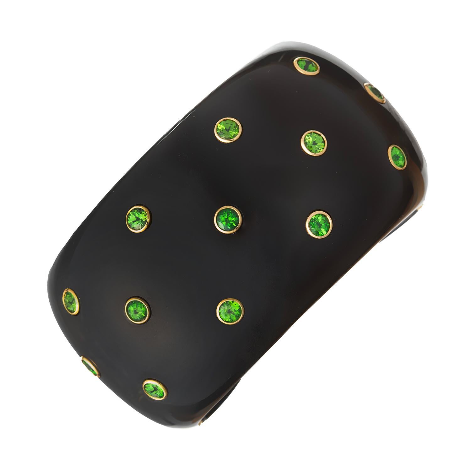 Cuff bracelet in carved and polished black jade accented by thirteen brilliant-cut demantoid garnets bezel-set in 18k yellow gold.  Hinged on one side of back, with 18k yellow gold fittings.