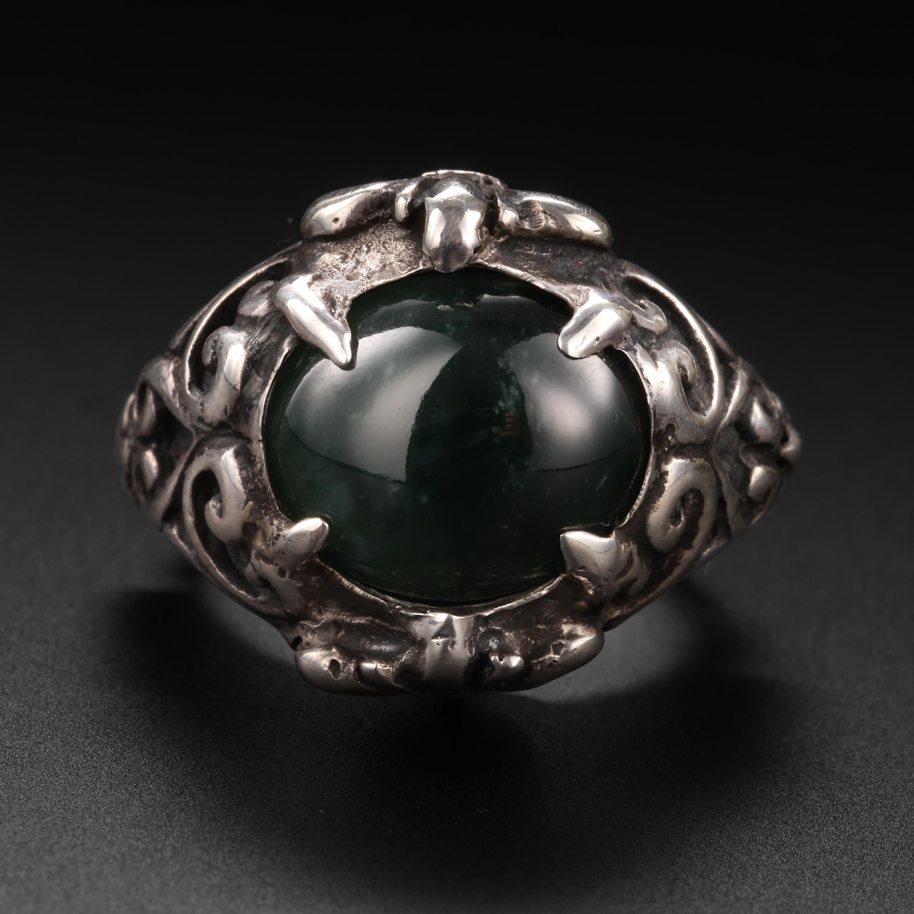 Looking like a ring straight from the 17th-century, this contemporary Baroque-style hand-fabricated silver ring showcases a high-polish oval cabochon of certified untreated black Burmese jadeite. Actually, it's dark green jade. But unless it's