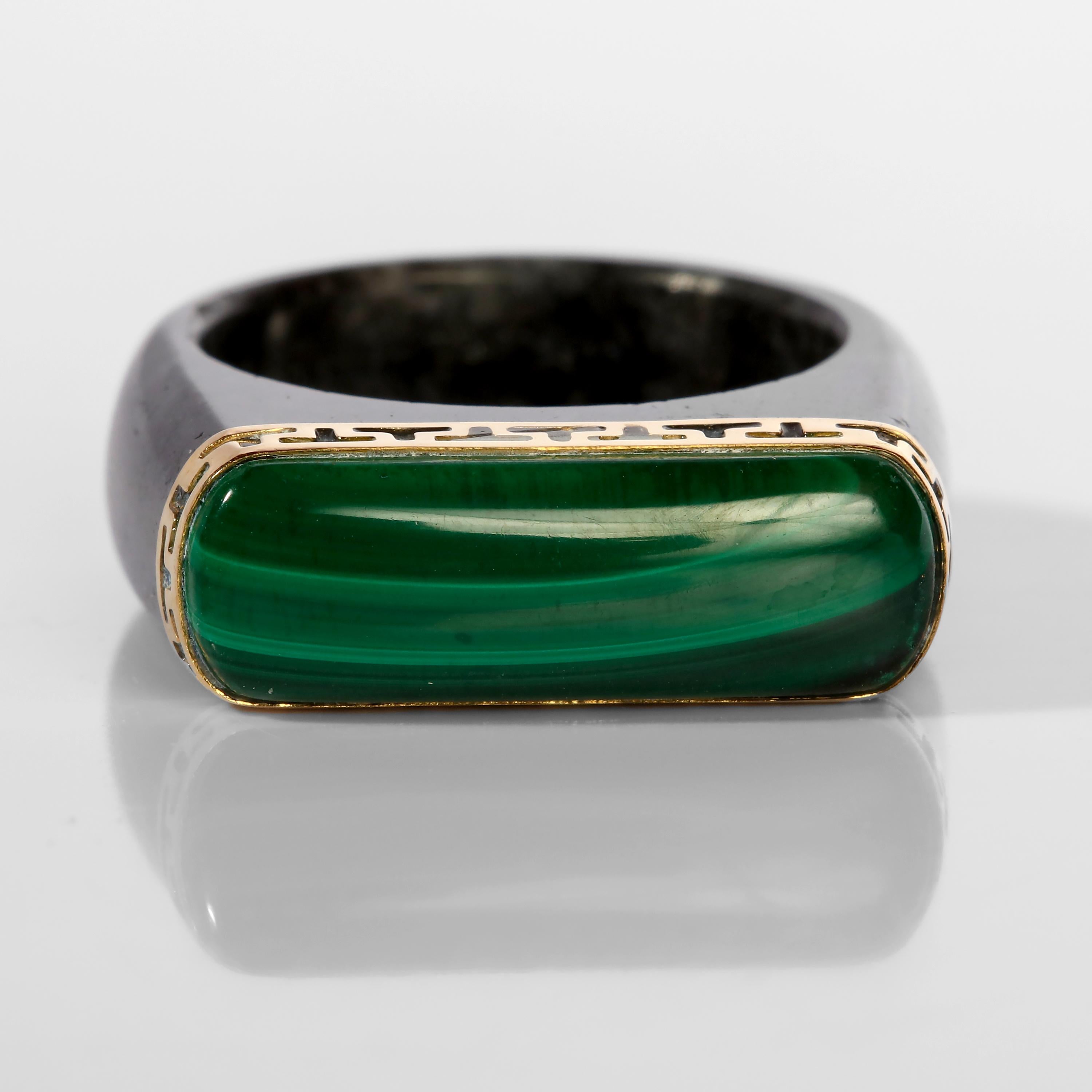 Here's a ring you don't come across every day or every other day or ever. A hand-carved natural and untreated black jadeite jade ring that is capped with a 14K yellow gold bezel featuring a pierced geometric design that resembles the letter 