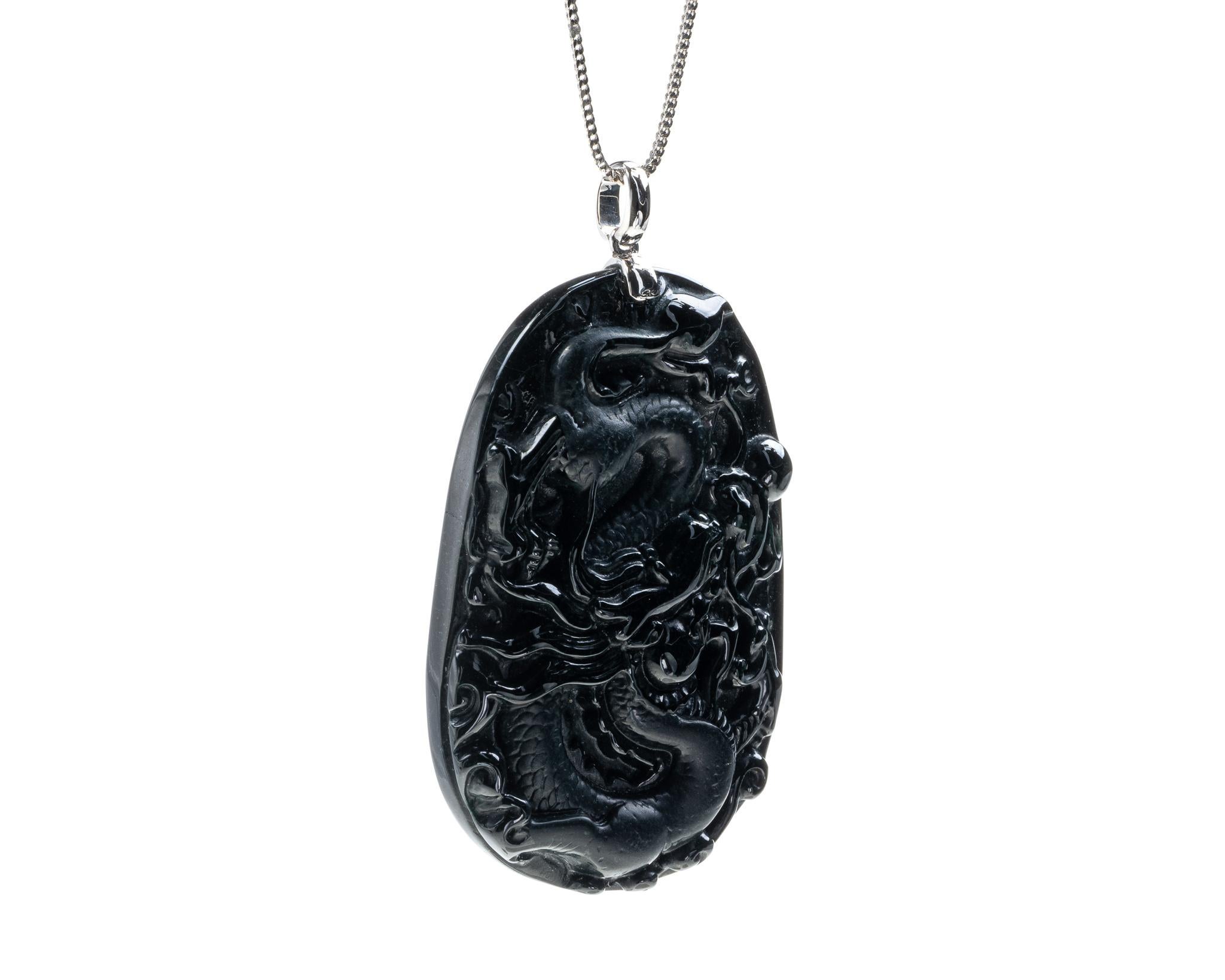 This is an all natural, untreated jadeite jade carved dragon pendant set on an 18K white gold bail.  The carved dragon symbolizes great power, good luck and strength.   

It measures 2.12 inches (54 mm) x 1.48 inches (37.6 mm) with thickness of 0.25