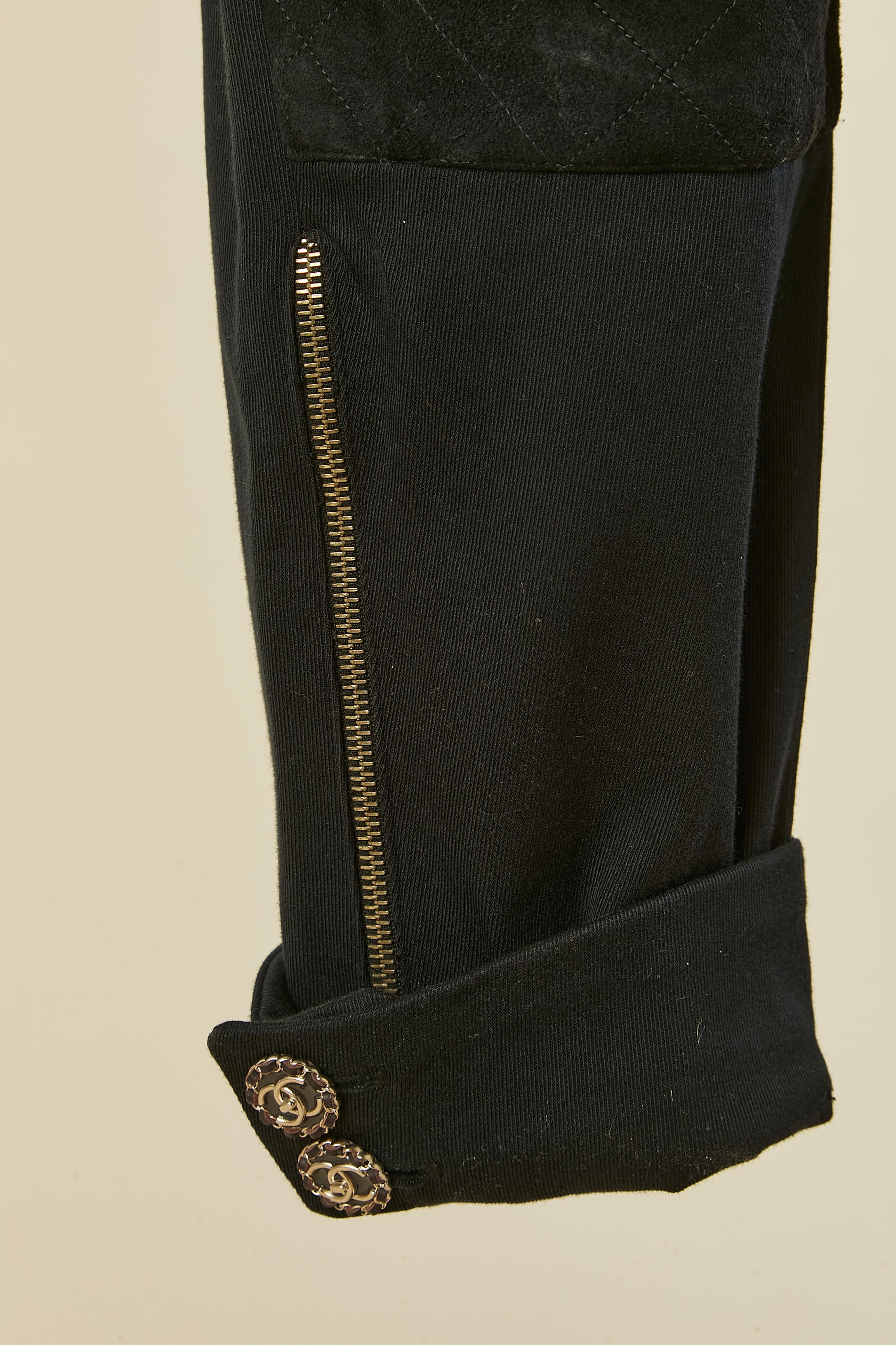 Pantalon Jodhpur noir avec application de daim surpiqué sur le devant des jambes. Bouton, boutonnière et fermeture à glissière marqués sur le milieu supérieur du devant. Bouton et boutonnière marqués sur la poche et sur le bas de la jambe + zip