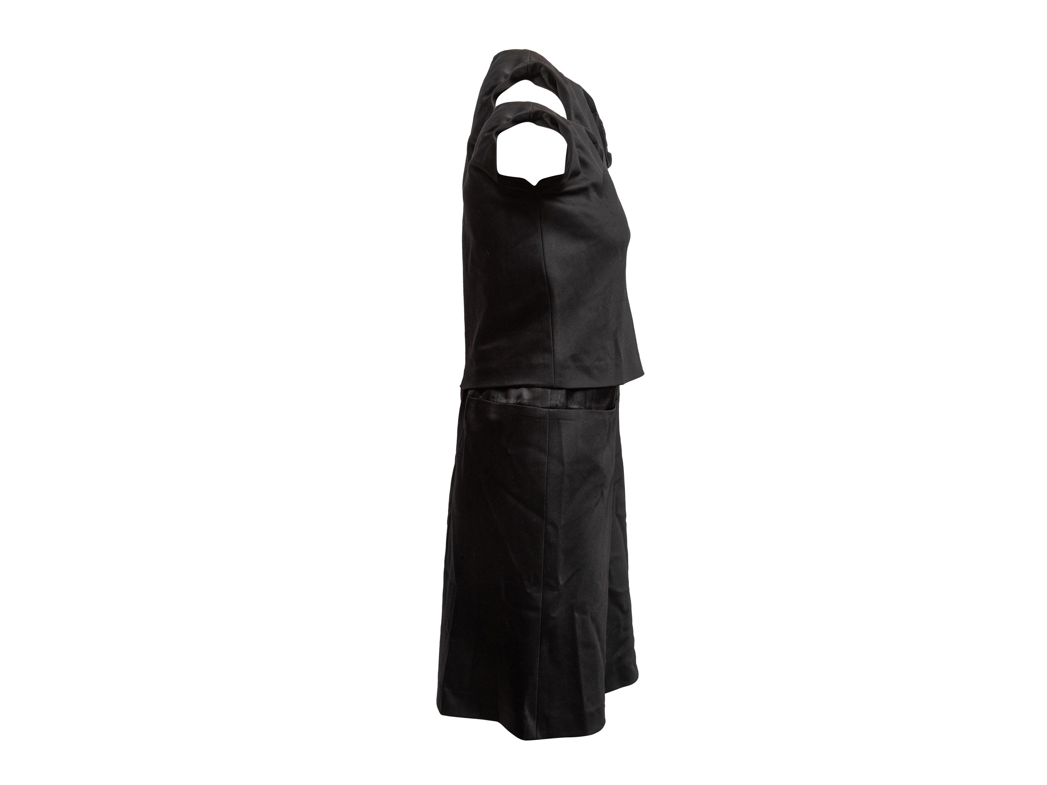 Vestido negro sin mangas de mezcla de lana de Kenzo. Cuello redondo. Detalles de roseta en el escote delantero. Cierre con cremallera en la espalda. 34