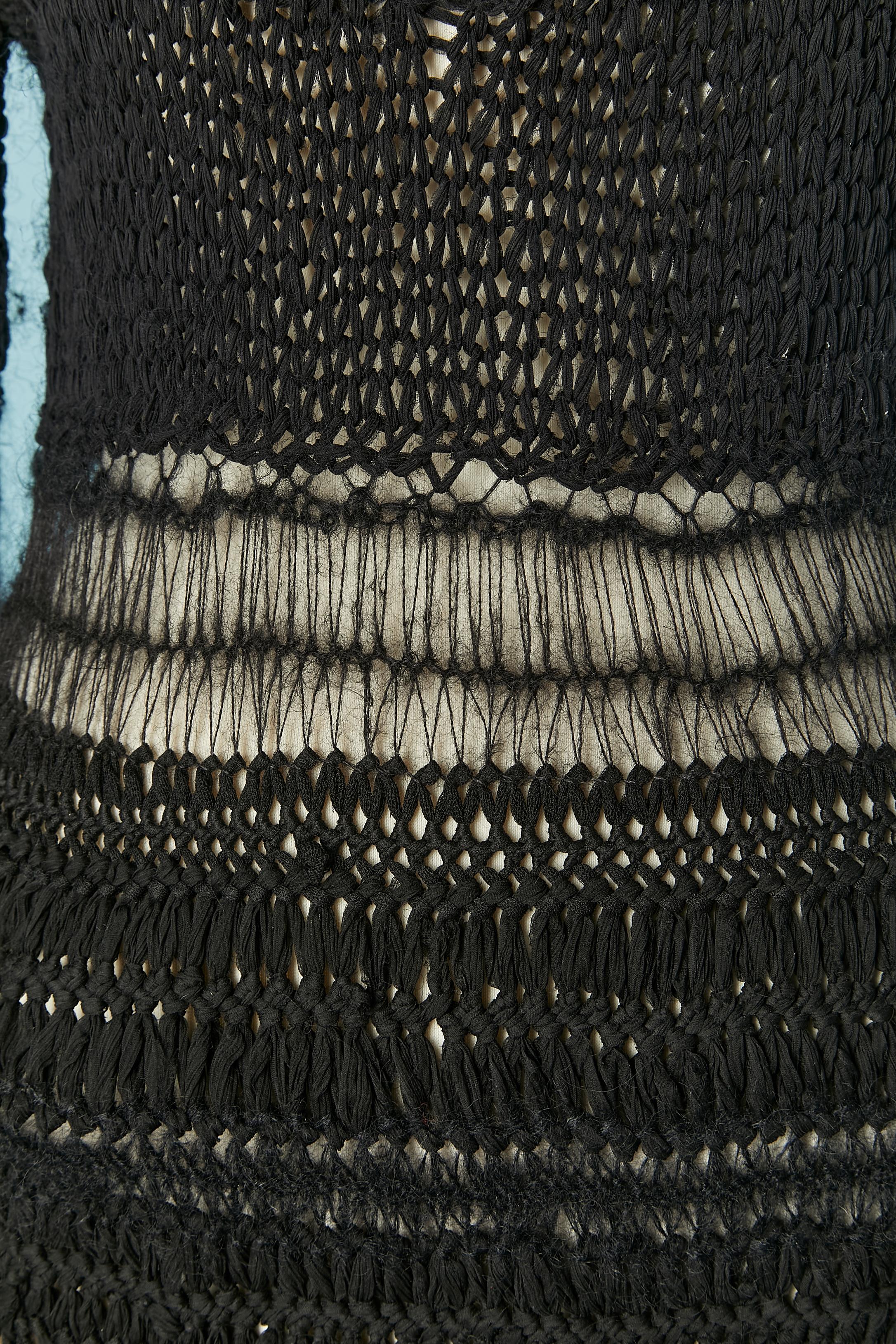 Black knit crochet dress with feather, fur and chiffon trim at the end of the sleeves and on the bottom edge. The knit is made of different threads. Button and buttonhole closure on the top middle back. 
SIZE 38 (Fr) M 