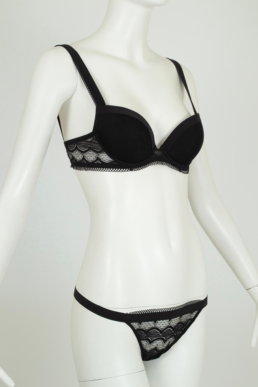 Set aus gepolstertem Bügel-BH und Tanga-Höschen. Büstenhalter mit Körbchen aus Nylontüll (mit Taschen für zusätzliche Polsterung, falls gewünscht) und breiten Trägern; Band aus geschwungener Spitze. Passendes Tanga-Höschen mit durchsichtiger,