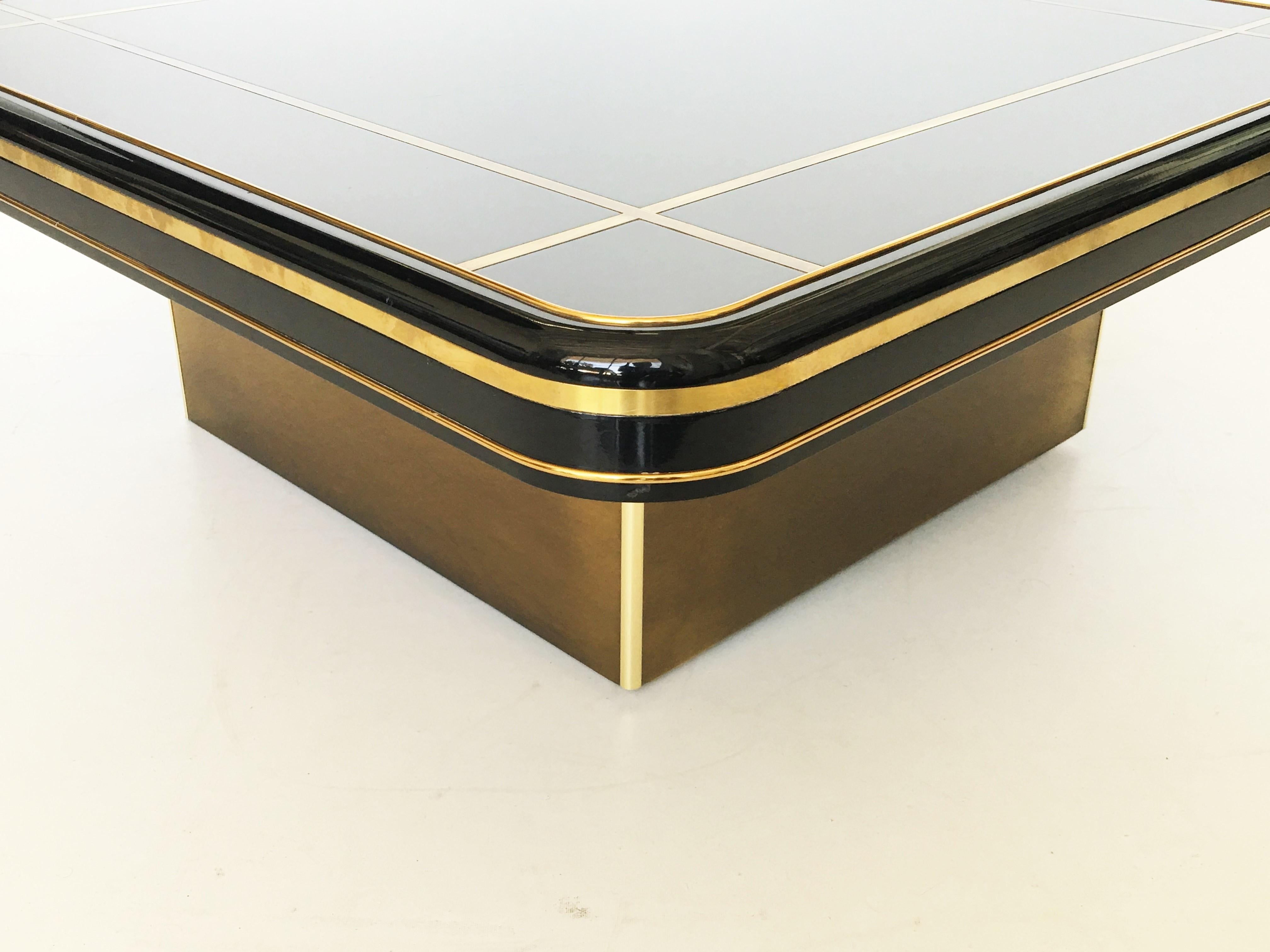 Mastercraft coffee table featuring a brass platform base supports a square top black lacquered surface with decorative brass inset and banding, with beautiful patina.