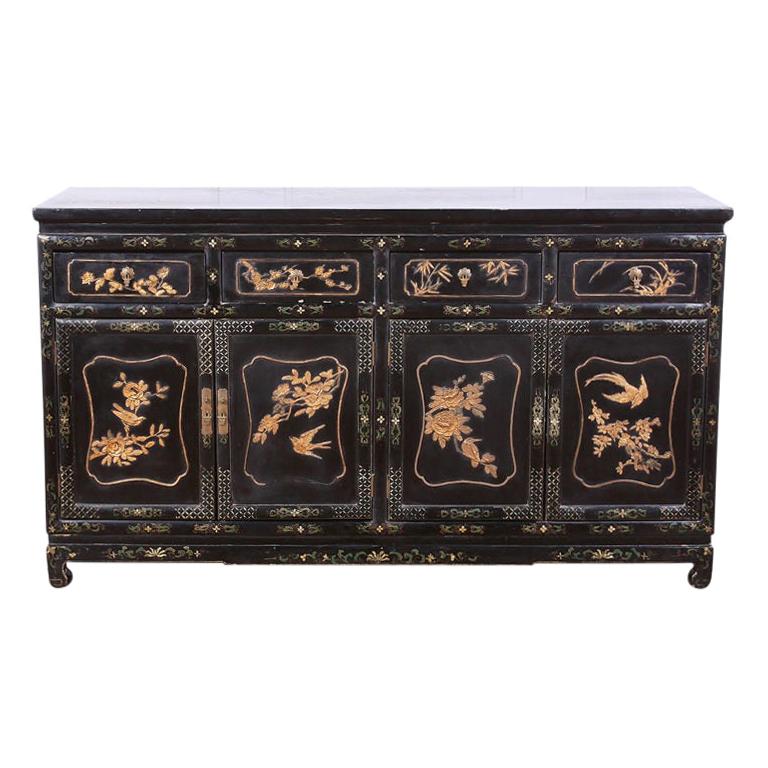 Black lacquer Asian sideboard embellished with detailed lacquered flowers and birds throughout and brass pulls. 



 