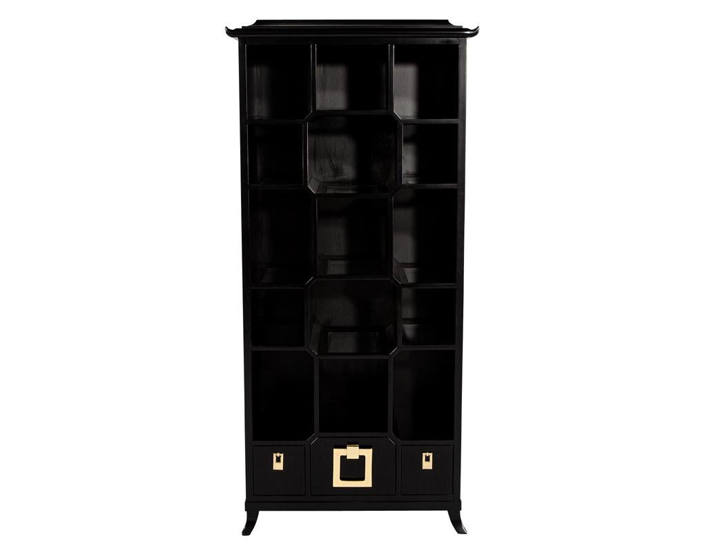 This stunning piece is expertly crafted and made in the USA, ensuring the highest quality and attention to detail. Drawing inspiration from iconic Chinoiserie style, this bookcase exudes elegance and sophistication. The rich satin black lacquer