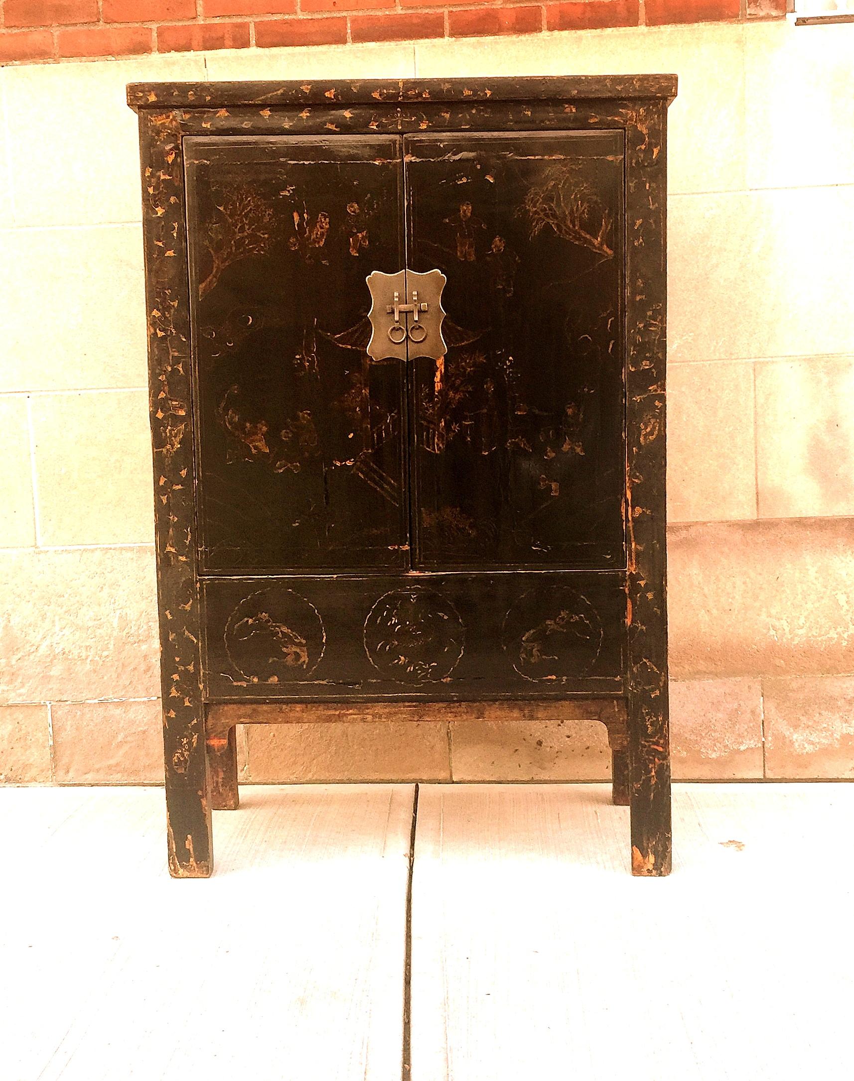 Black lacquer cabinet with gilt garden scene motif. Pair of open doors with brass fittings. Inside with drawers shelf.