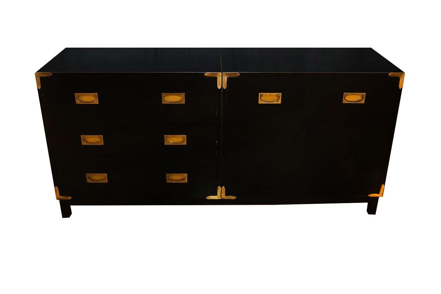 This striking custom black lacquered sideboard has a classic campaign design, fashioned out of two smaller chests, to create one larger unit, adorned in brass trim on sides and front. The left side features three symmetrical stacking drawers with