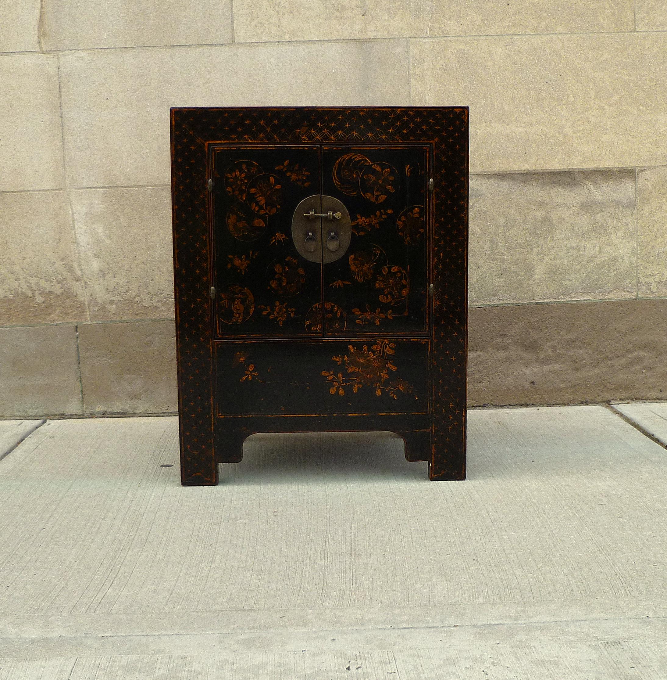 Black lacquer chest with gilt motif with pair of open door and shelf inside.
