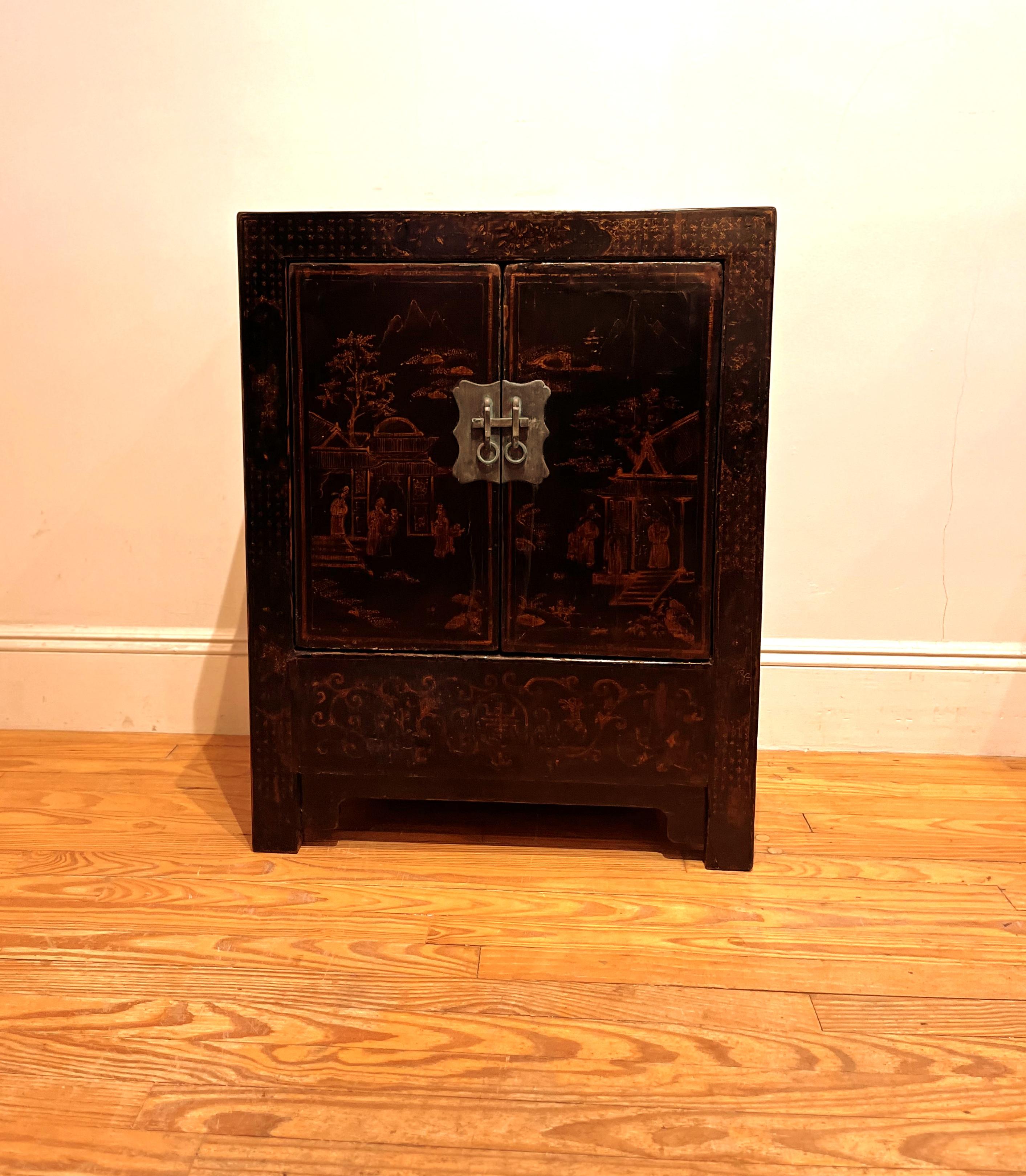 Black lacquer chest with landscape gilt motif with pair of open door and shelf inside.