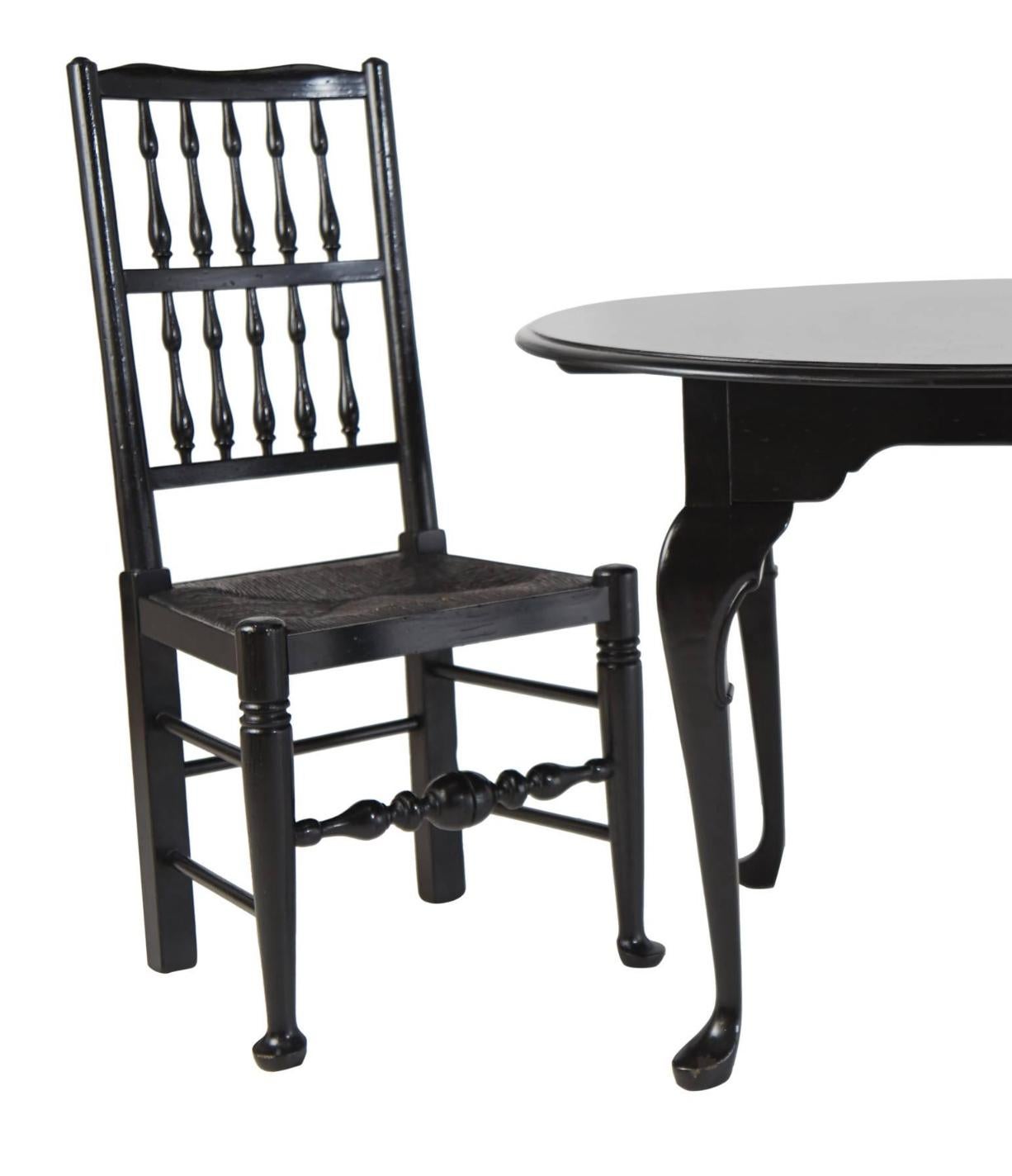 Pair of two Colonial Revival style chairs and Queen Anne style round table that have been refinished in a high gloss black lacquer. The chairs feature turned spindles and stretchers, pad feet and rushed seat. The round table comprises of curvaceous