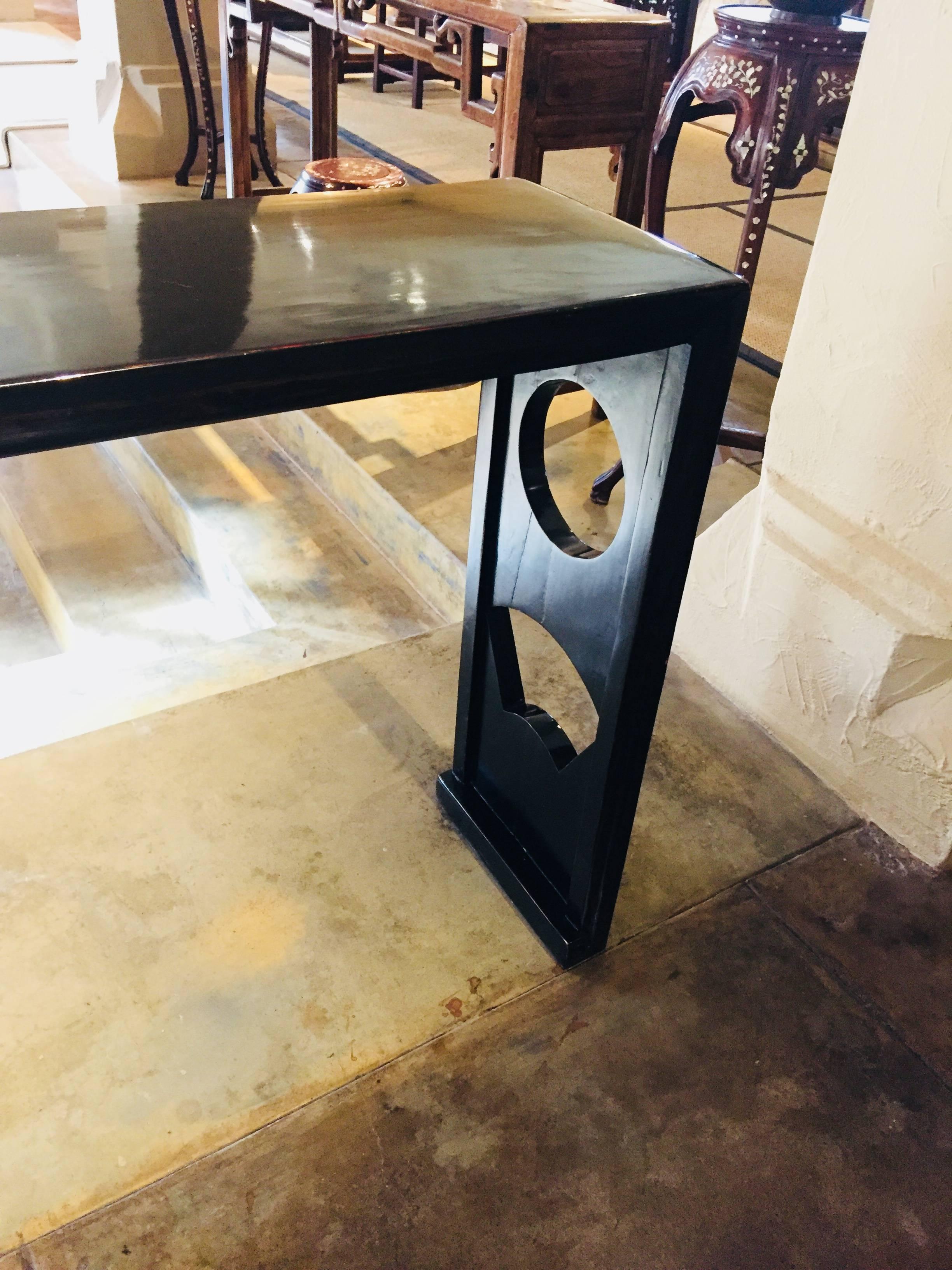 This unique black lacquer wood console table is from China from the Shanxi Province.
It is 75 L x 12 D x 33 H

It has a modern look with the cut outs in the legs, circle and a half circle. 

The finish is lovely.