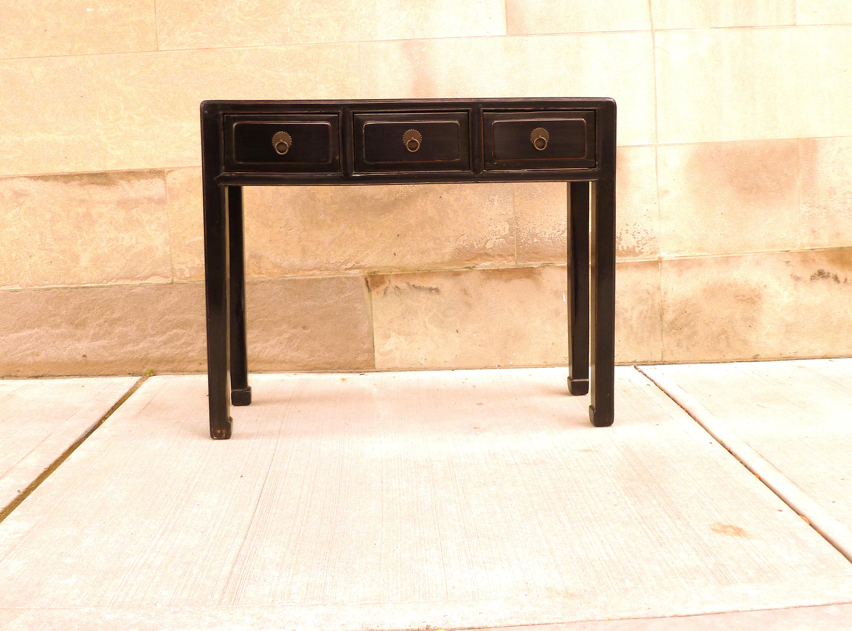 Black lacquer console table with three drawers with hoof feet.