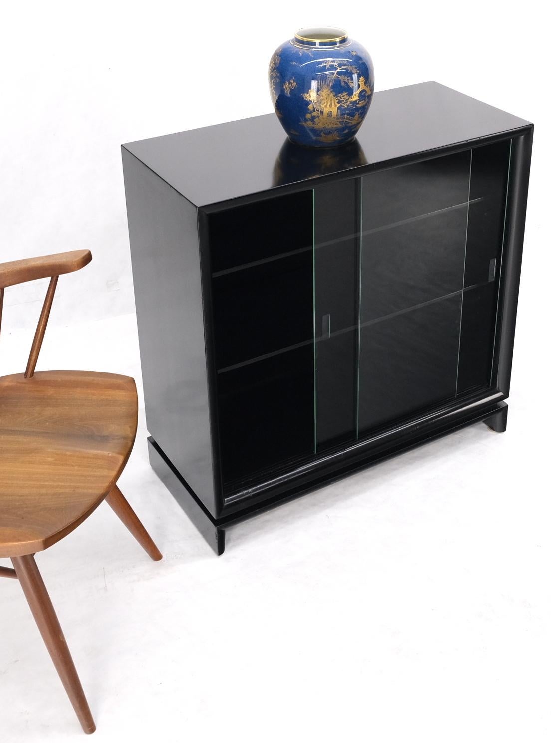 Black lacquer double glass sliding doors bracket feet petit bookcase shelves.