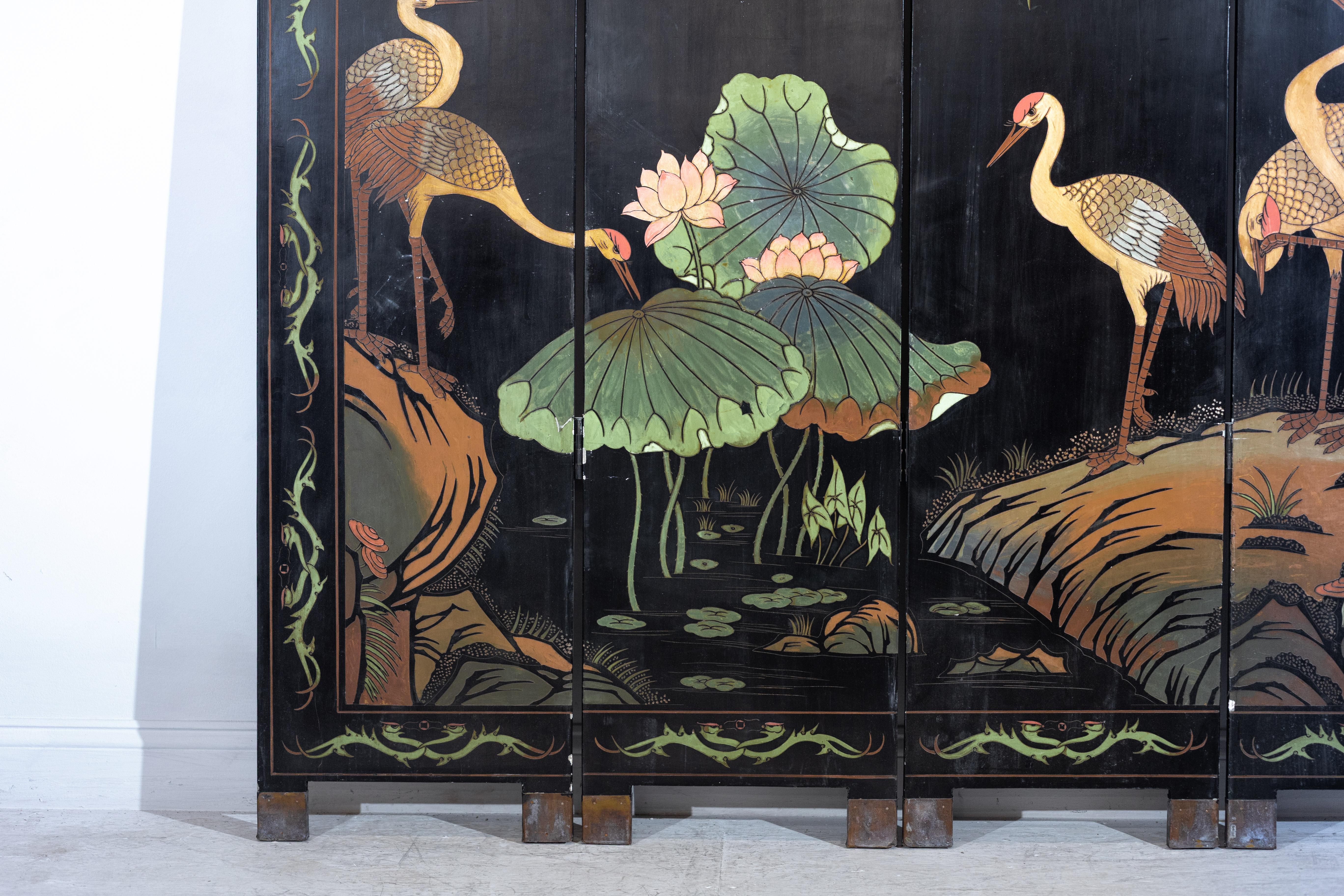 Dieser detailreiche und visuell fesselnde vierteilige handbemalte Paravent im Vintage-Stil zeigt ein auffälliges Tableau von Kranichen mit roten Hauben und Lotusblüten vor einem dramatischen schwarz lackierten Hintergrund. Die handgemalte Szene