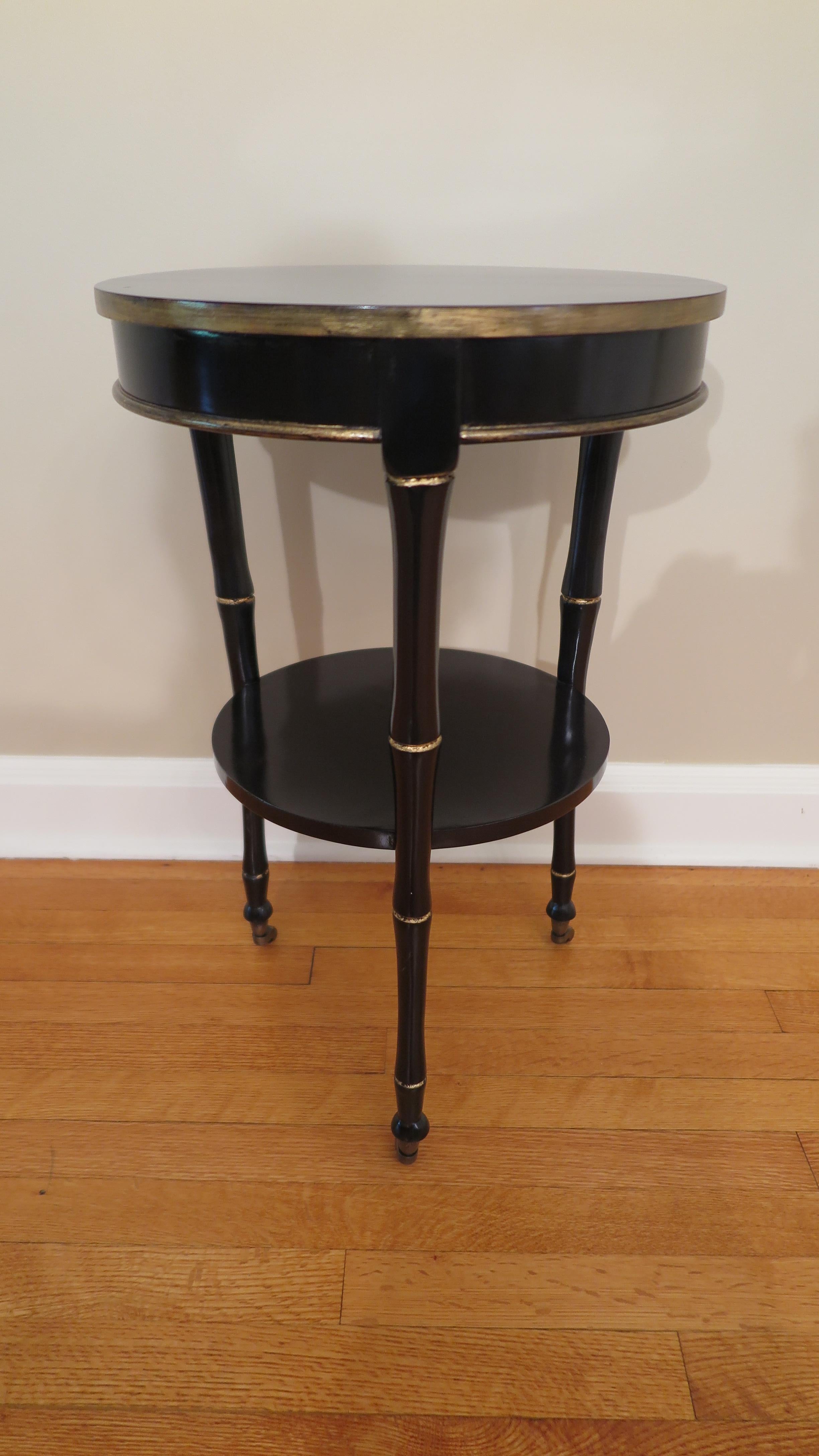 Elegant black lacquer gueridon side table. Exceptional side table having three legs shaped as bamboo with a lower shelf as strut, gilt detail accents and caster feet. Finely crafted table of high quality. Classic elegance. Very good to excellent