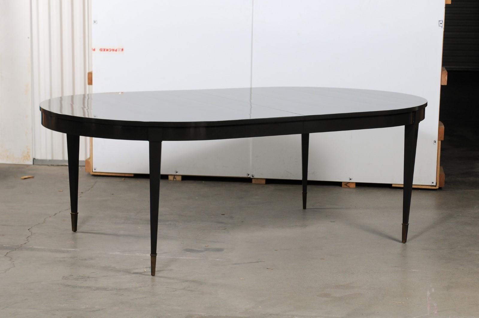 Thomas Pheasant for Baker oval dining table that has been refinished in Benjamin Moore, black satin #2131-10 with a lacquer finish. The oval top rests on a conforming apron with four tapering legs, and leaves that can be removed as needed. Please
