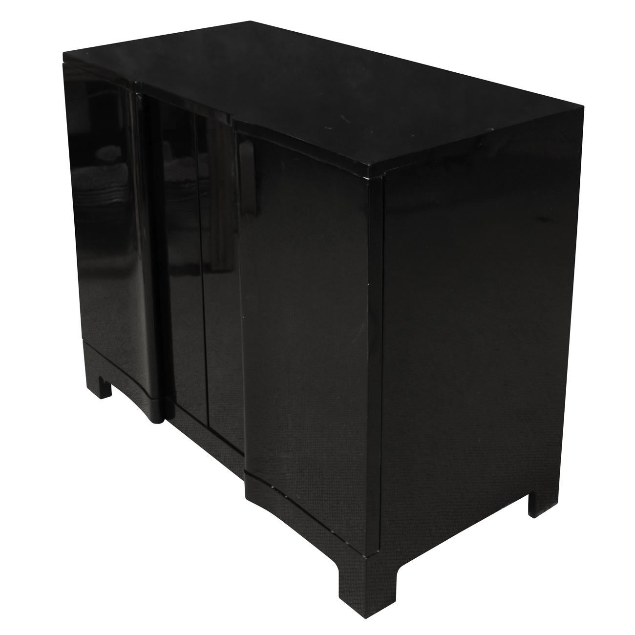 Modern black lacquered cabinet with curved front appearing as three doors. Cabinet has two doors that swing open to reveal three shelves for storage.