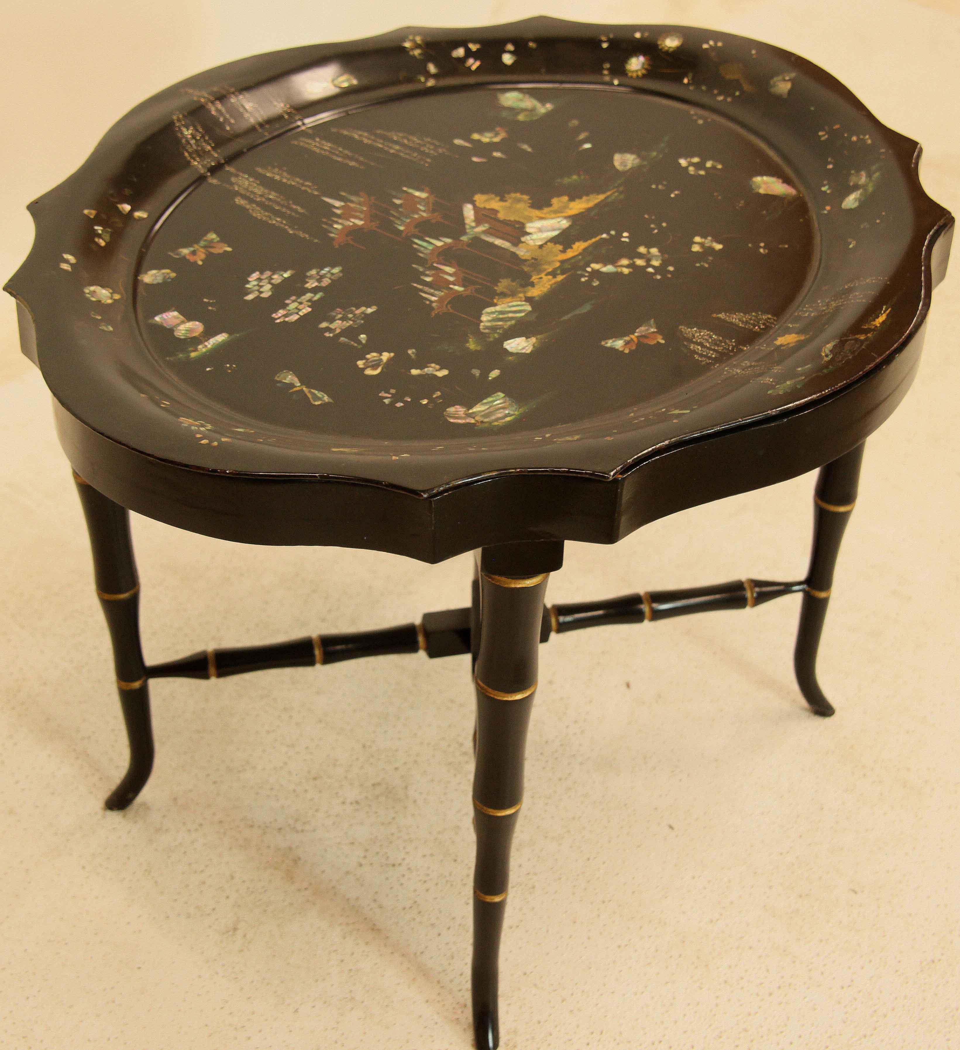Black Lacquer tole tray table with scalloped edges has Japanese influence,  the border is decorated with dragon flies, stylized flowers and mother of pearl designs; the body of the tray with similar dragon flies, butter flies, flowers and mother of