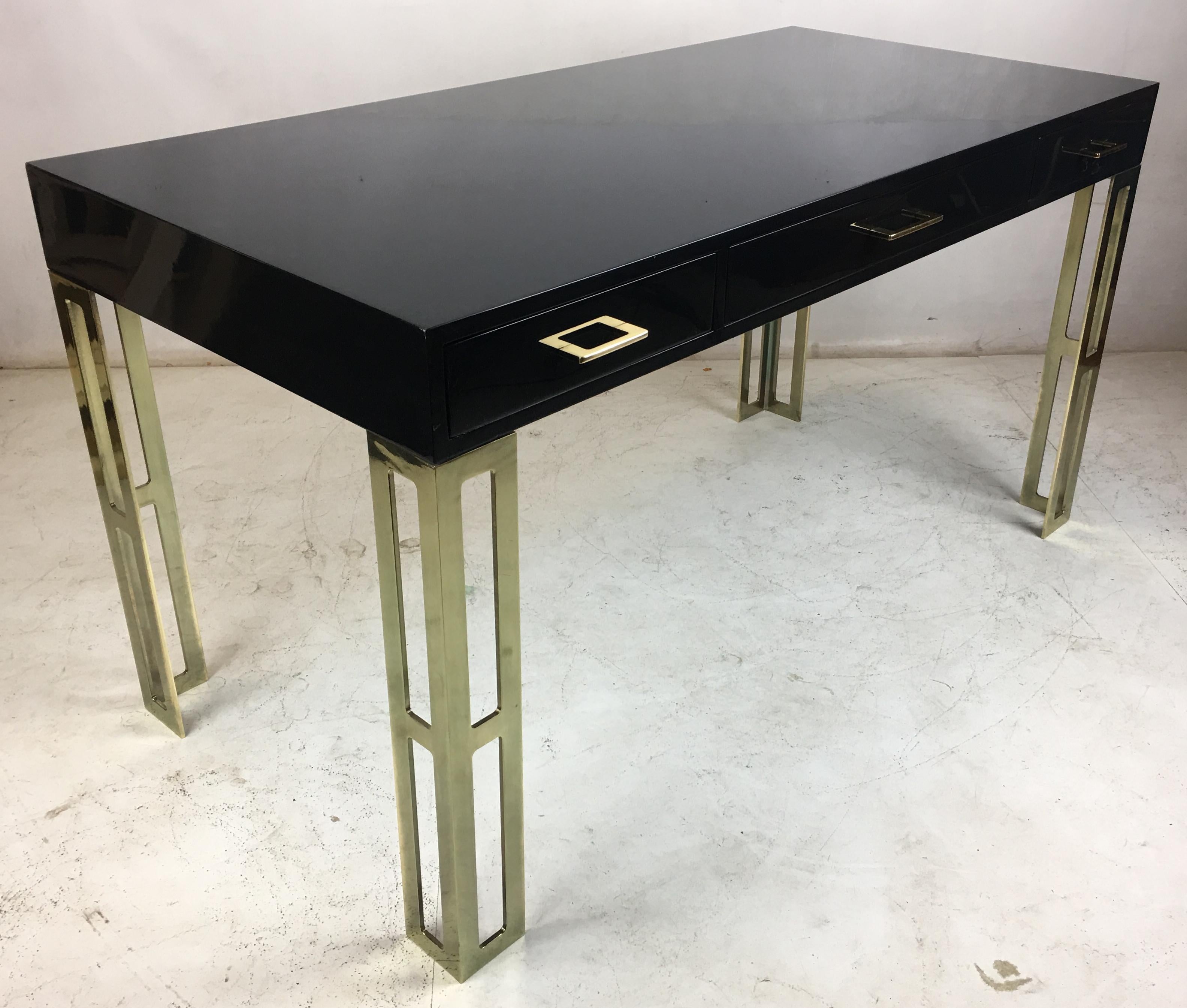 Elegant black lacquer writing desk with polished brass legs and drawer pulls. The desk, with its three drawers, has been freshly lacquered and hand polished to a high gloss and the brass hardware has been professionally polished and lacquered to