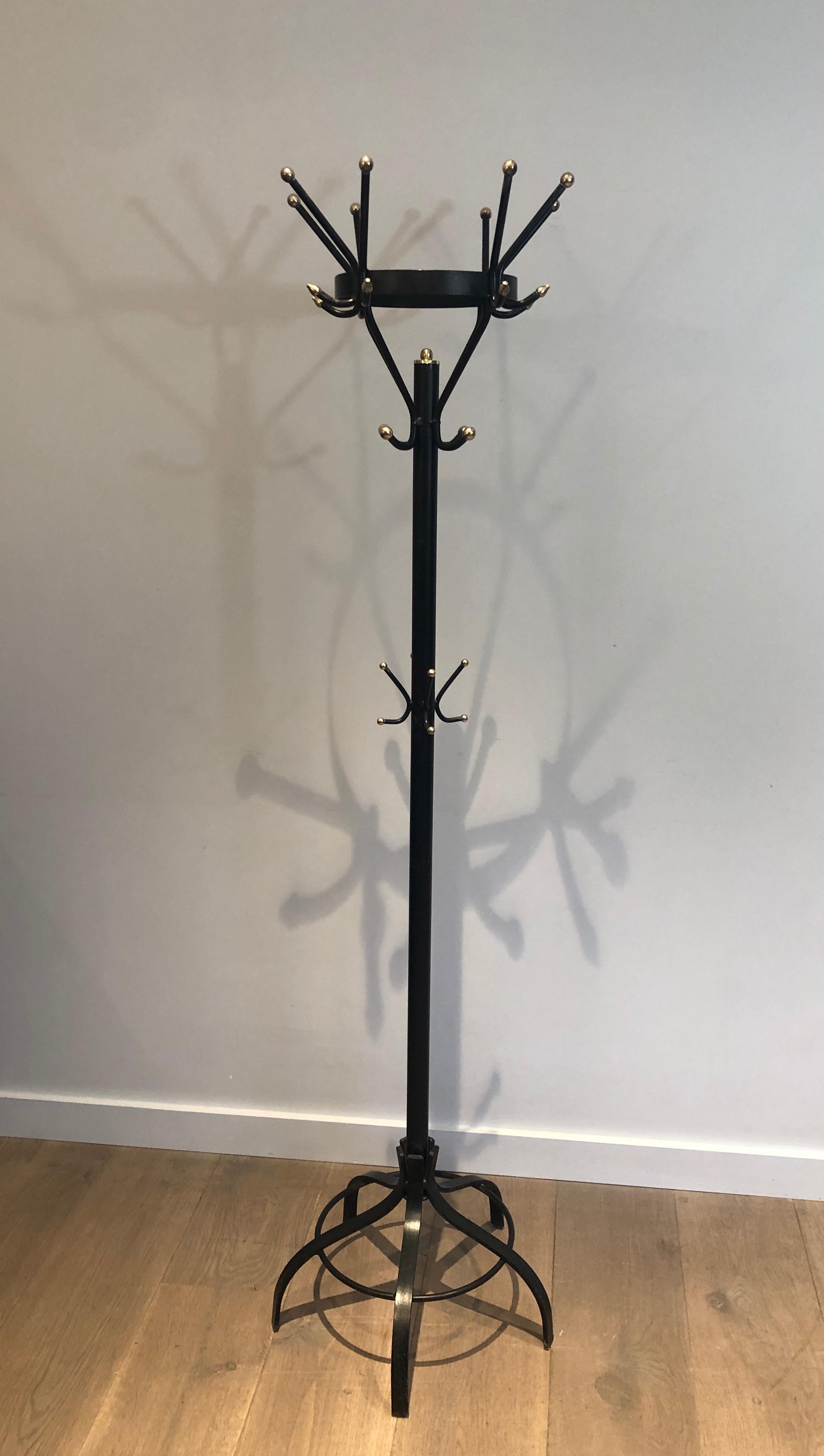This unusual design coat hanger is made of black lacquered metal and brass. This is a French work. Circa 1950.