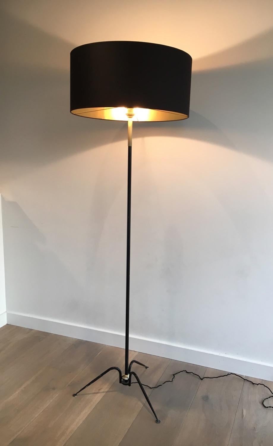 This floor lamp is made of black lacquered metal and brass with a new shade made of black shintz, gilt inside. This is a French work and a very nice design, circa 1950.