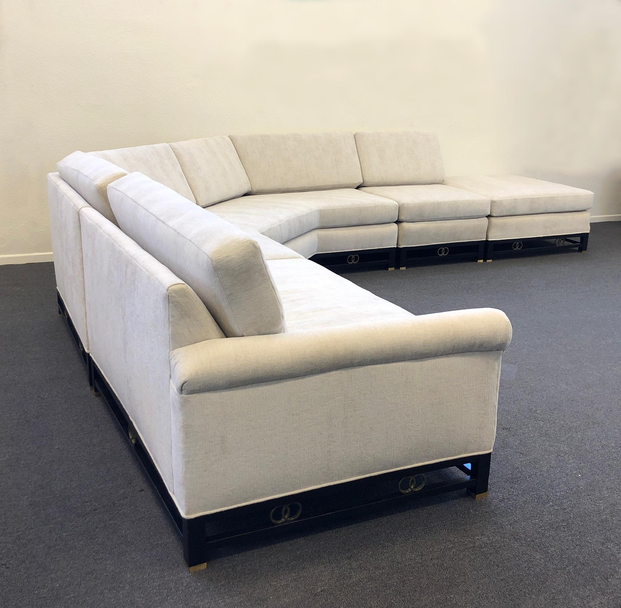 1950’s four piece black lacquered and brass with off white fabric sectional sofa by Michael Taylor for Baker Furniture Co. 
Newly recovered with a soft off white chenille fabric. The legs are black lacquered wood with brass details. 
It can be