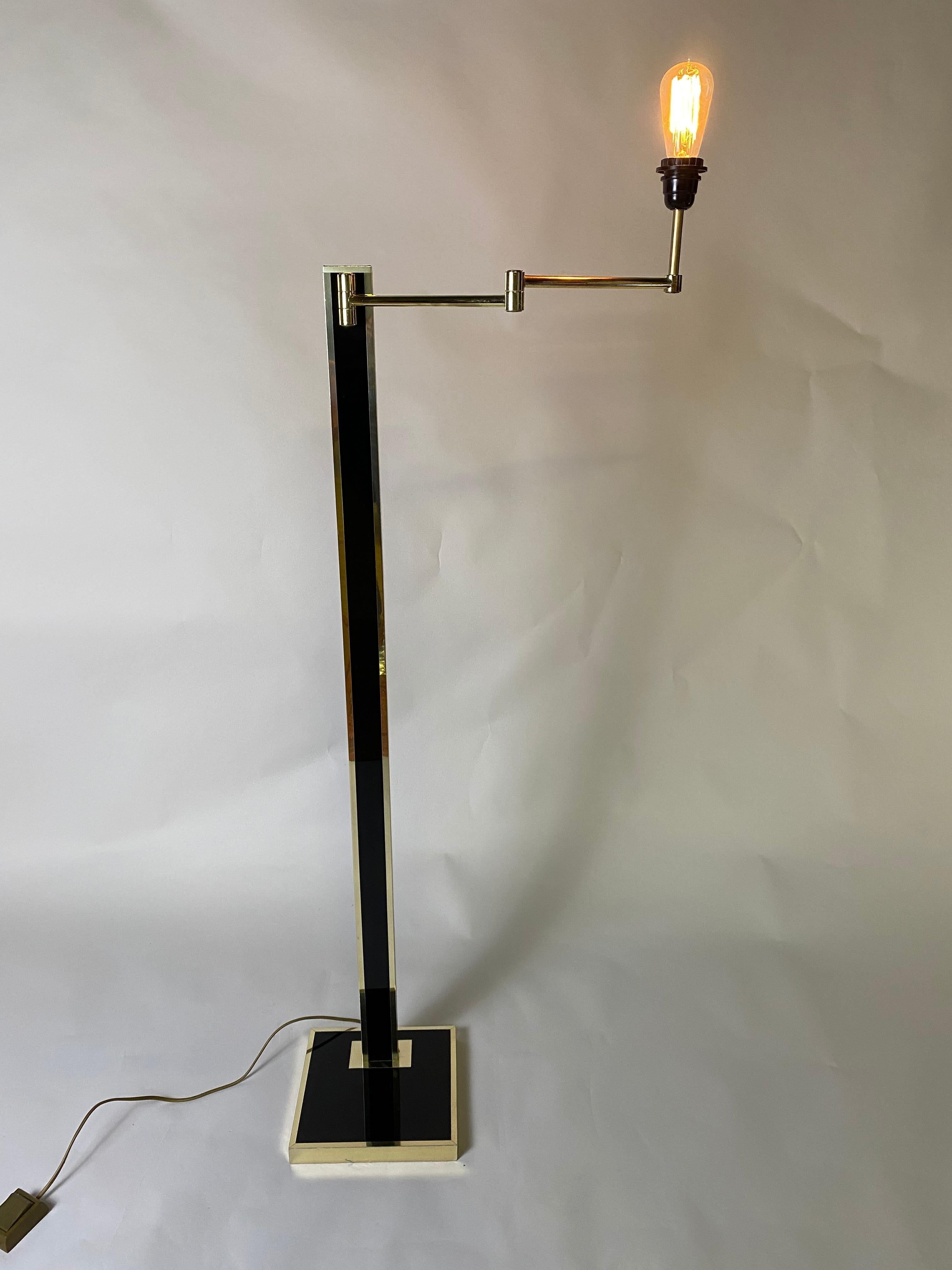 Vintage Hollywood floor lamp, 1980s. The lamp has a movable arm. The lamp is kept in good condition. The lamp is made of black lacquered and brass metal. A heavy base makes it a very sturdy lamp. There are minor scratches on the base. Bulb with E27