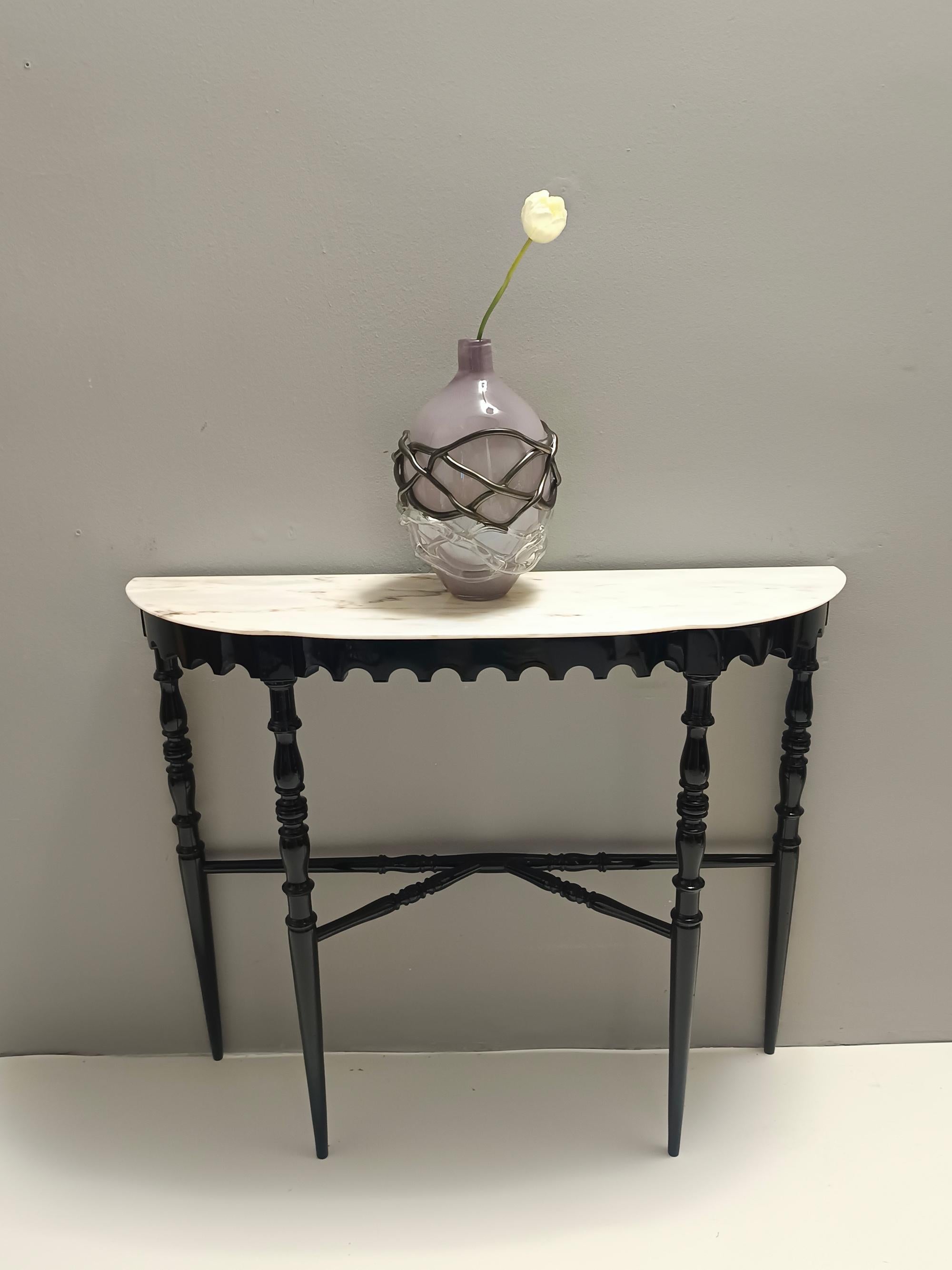 Made in Italy, 1960s.
This refined console table is made in black lacquered sharped and turned beech and features a demilune Portuguese pink marble top. 
It is a vintage item, therefore it might show slight traces of use, but it can be considered as