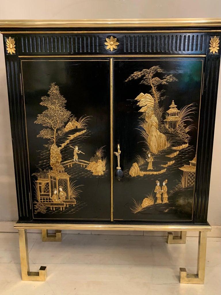 Antique Chinese cabinet with hand-painted décor depicting people and traditional architectures in a landscape. The doors and the sides are hand-painted with floreal scenes, presenting characters set among traditional structures. The lighter tones of