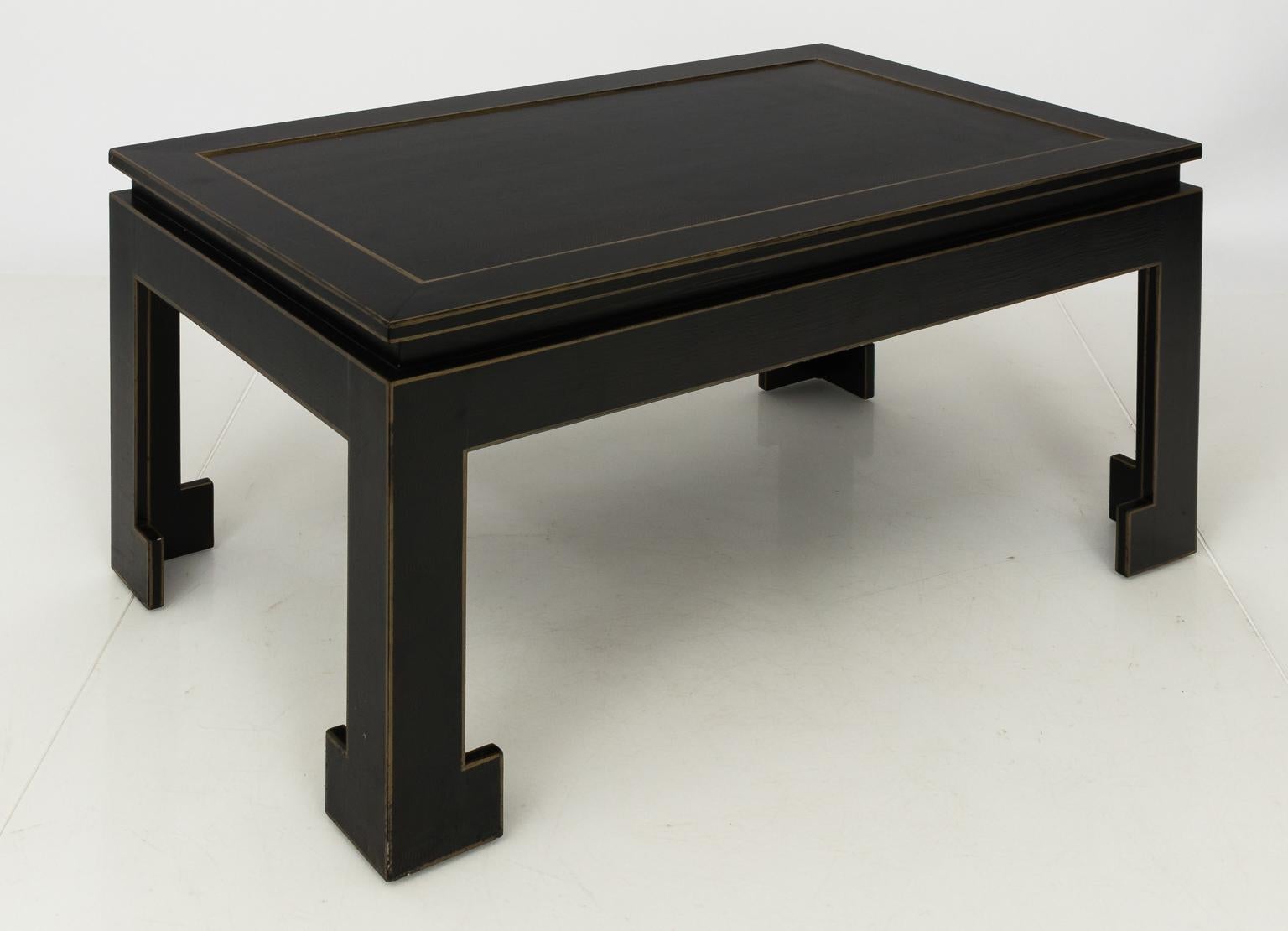 Contemporary black lacquered Chinese coffee table with gold painted trim and bracket legs.
 