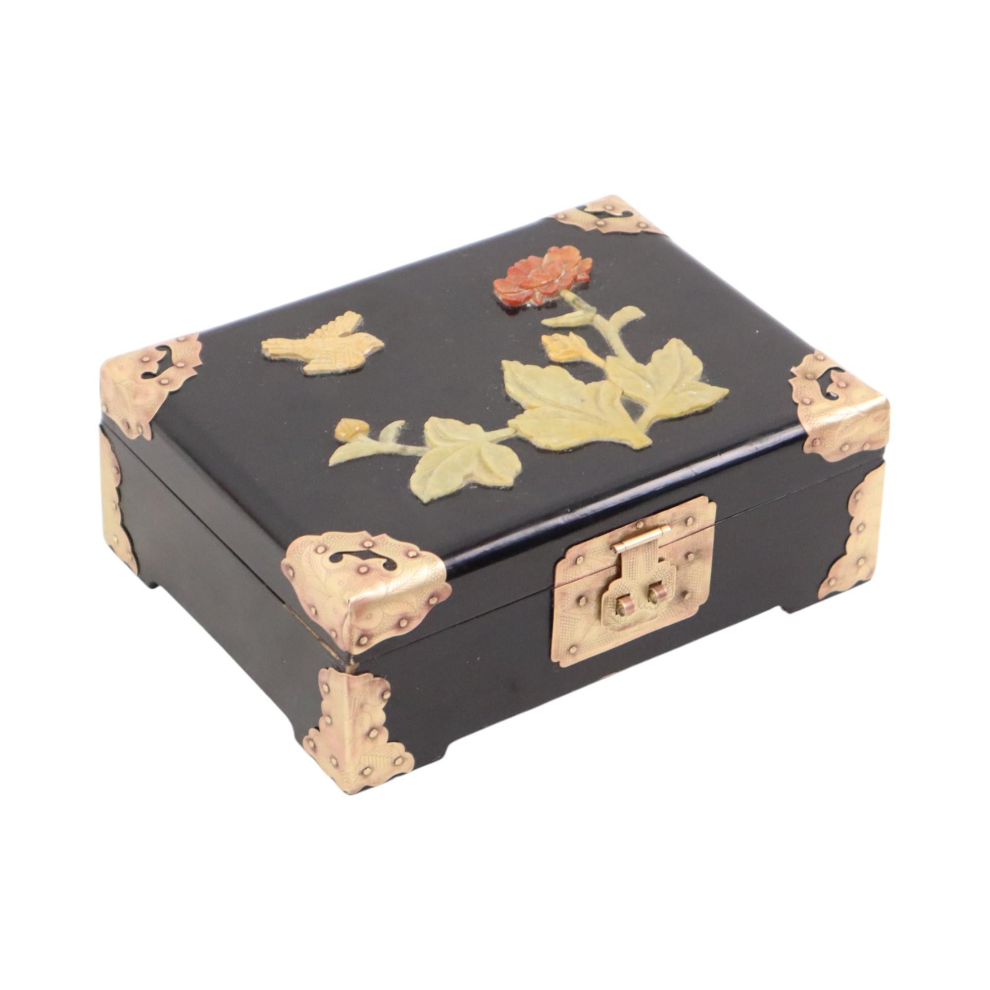 Joyero chino vintage, joyero chinoiserie, de madera lacada en negro, detalles de latón e imagen de piedra jabón en relieve de flores y un pájaro, forrado por dentro con una lujosa tela roja y provisto de un espejo, ca. 80, China.

Cada esquina de